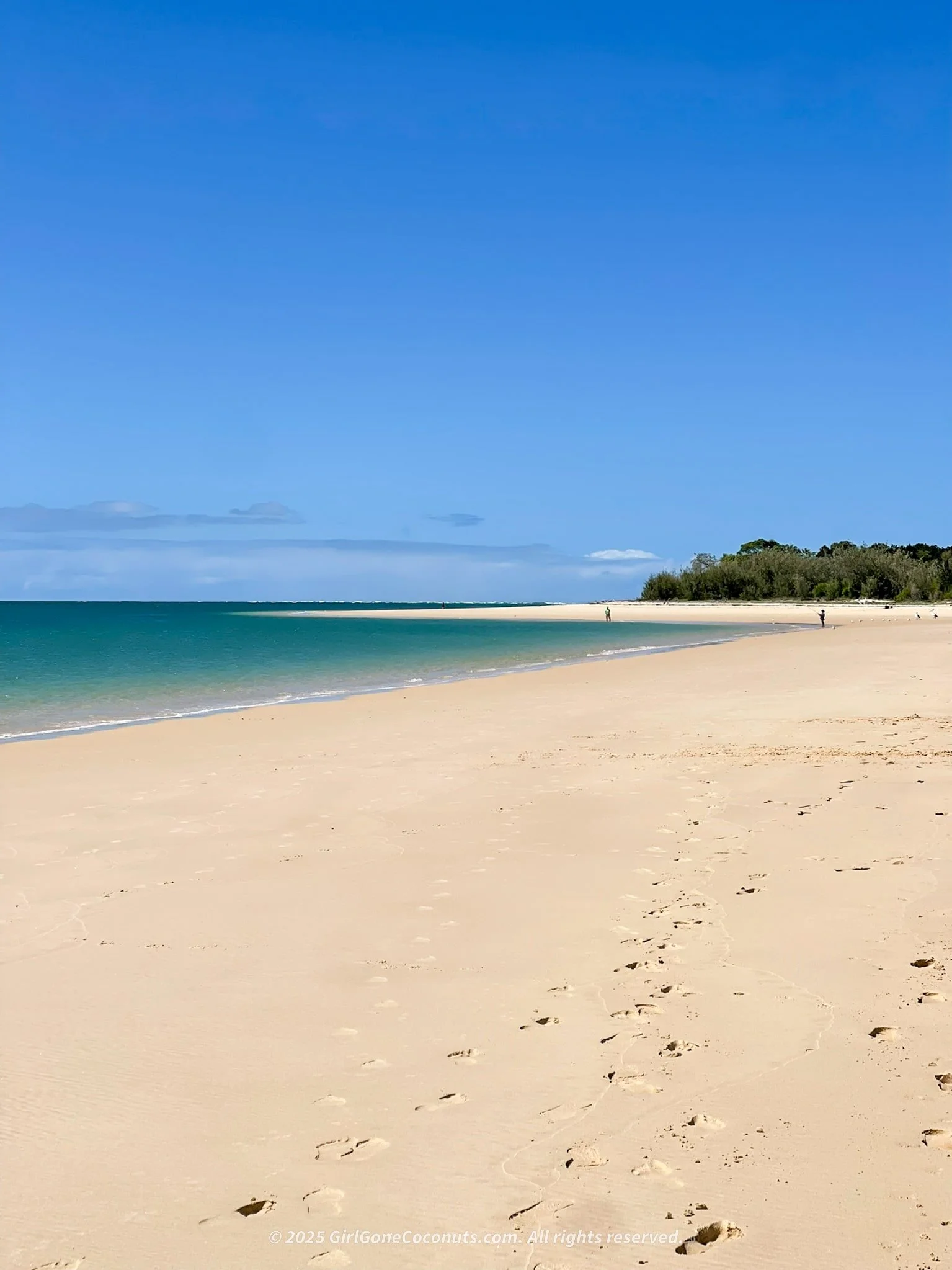 Coastline view of Inskip Point in Rainbow Beach with people swimming, boating, and fishing in the background.