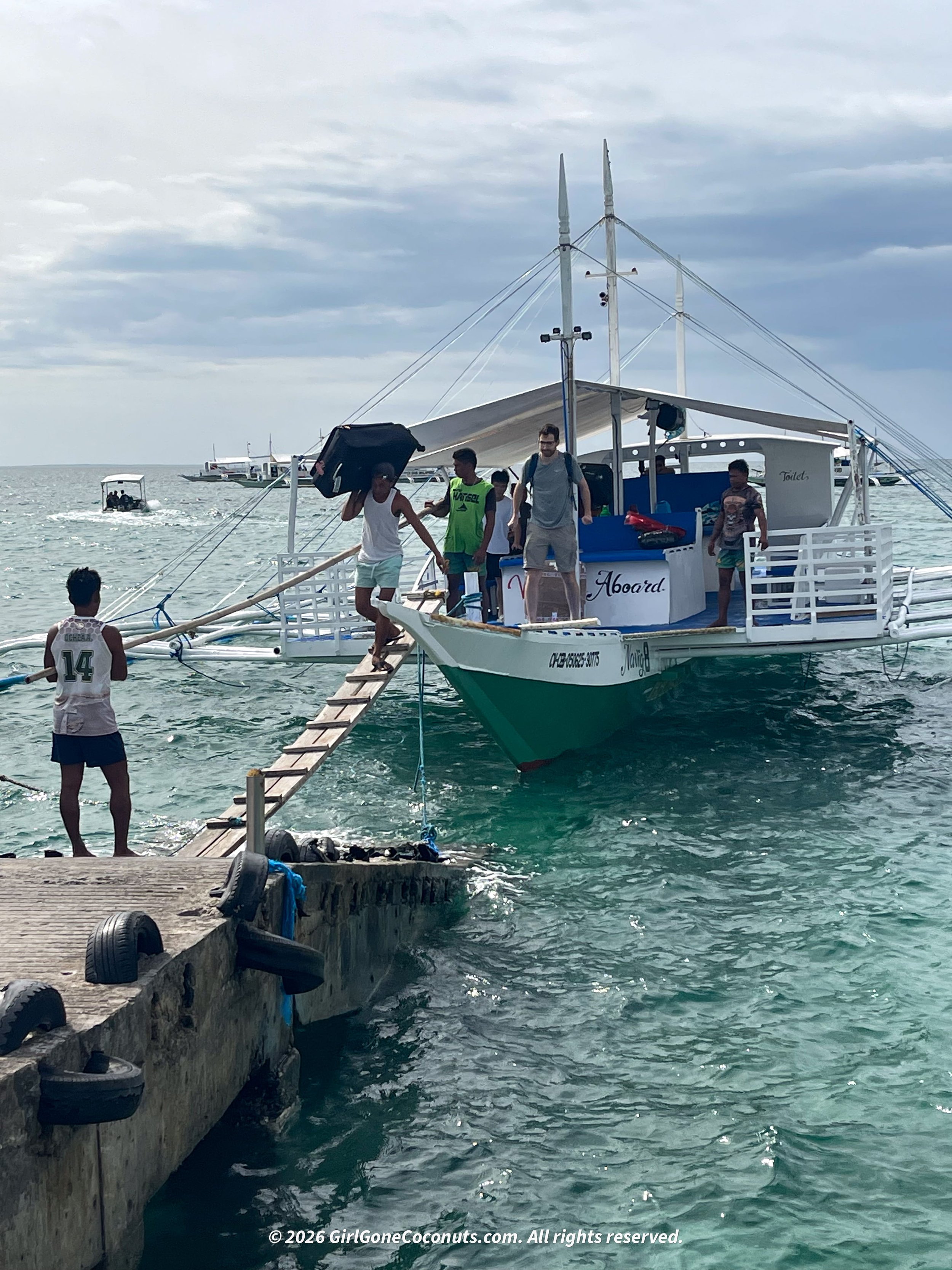 The boat workers carrying the luggage off of the boat in Malapascua.