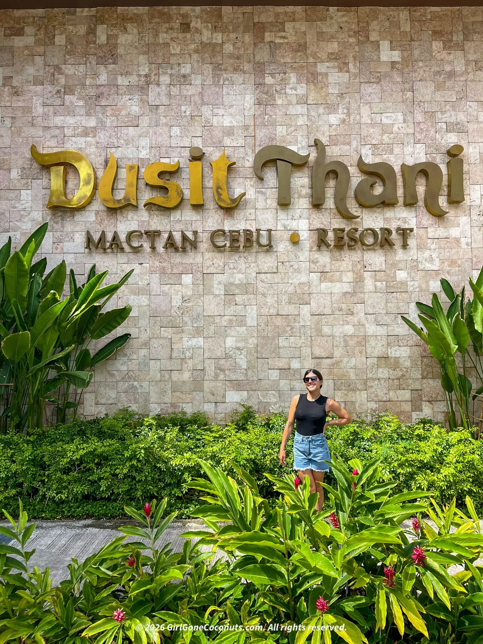 Traveler smiling in front of Dusit Thani Resort sign.
