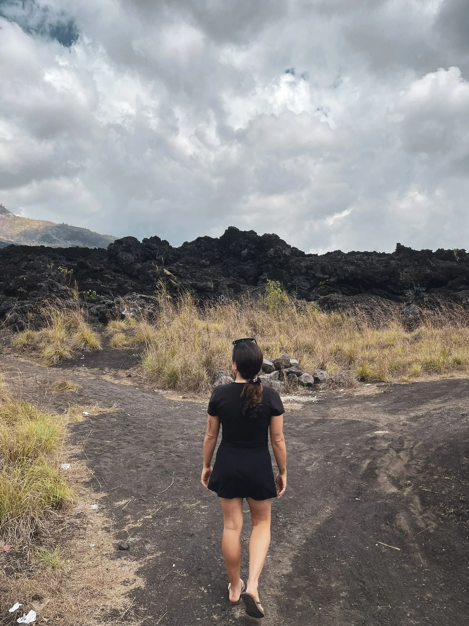 Traveler walking toward the black lava fields of Mount Batur in Kintamani, Bali.