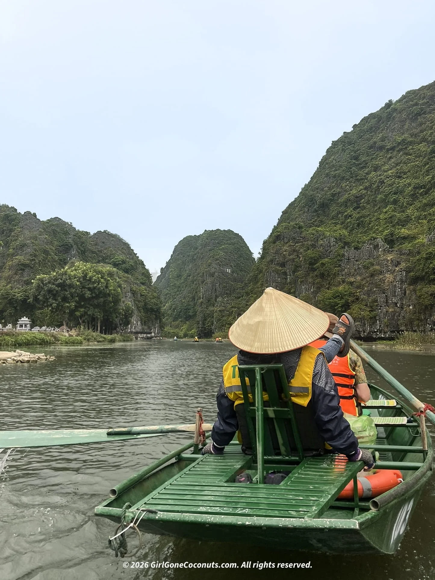 Driver paddling boat through Tom Coc with their feet.