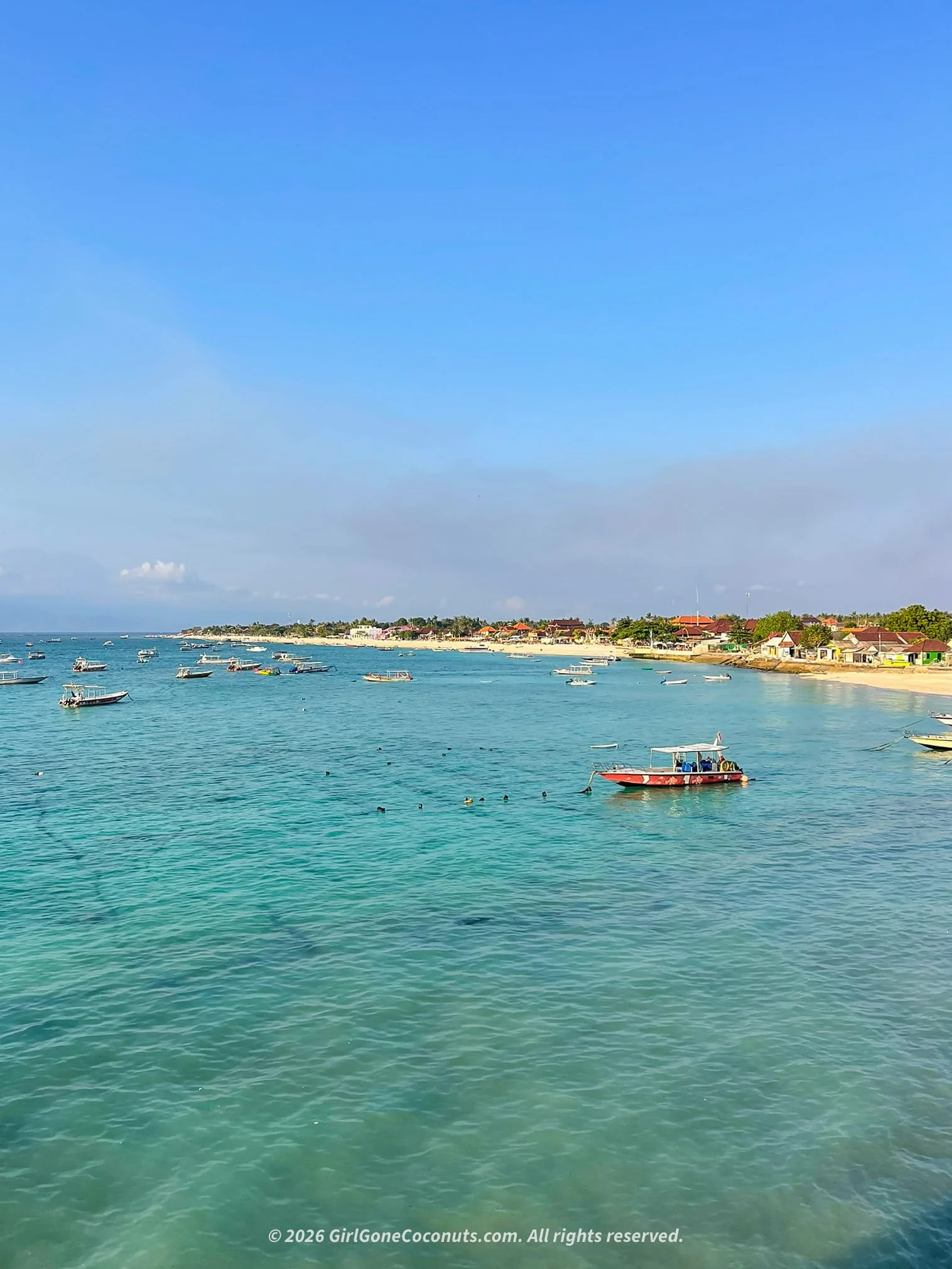 Dreamy views over Nusa Lembongan's turquoise coastline, lined with hotels, restaurants, and local boats.