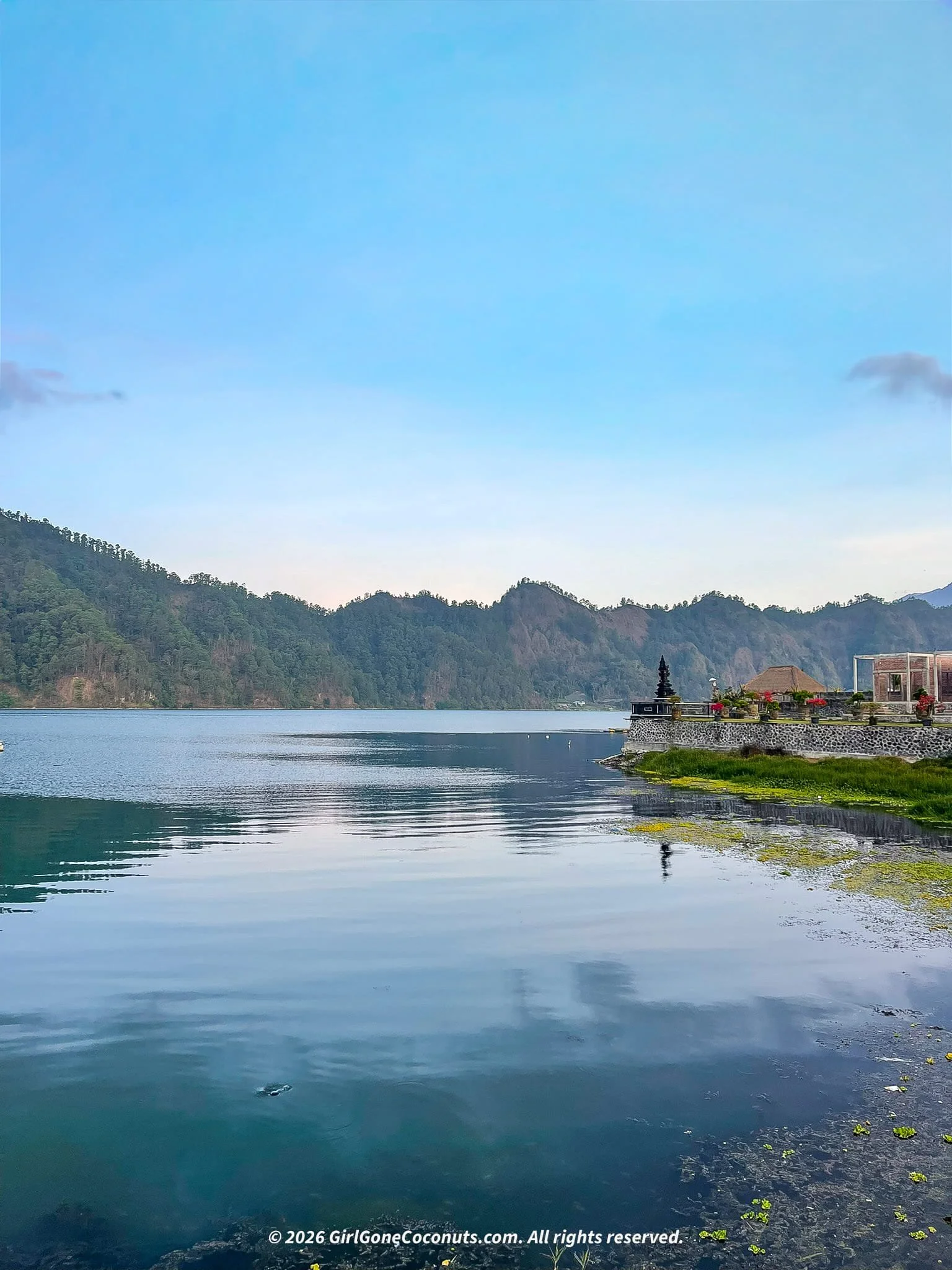 Lake Batur at dusk with Pura Segara Ulun Danu Batur temple visible on the shoreline, Kintamani Bali.