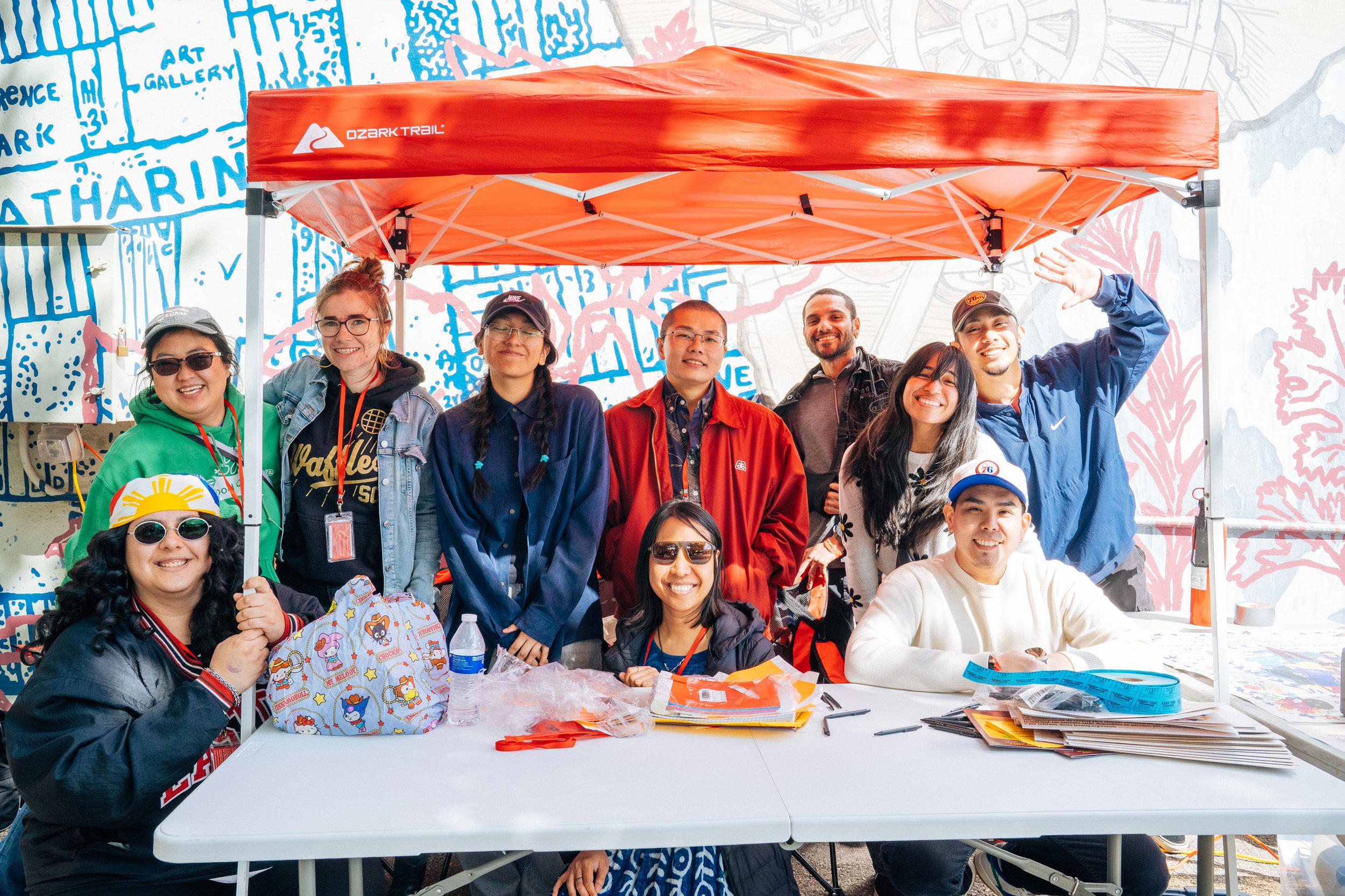 A group photo of 10 volunteers posing in front of a red tent.