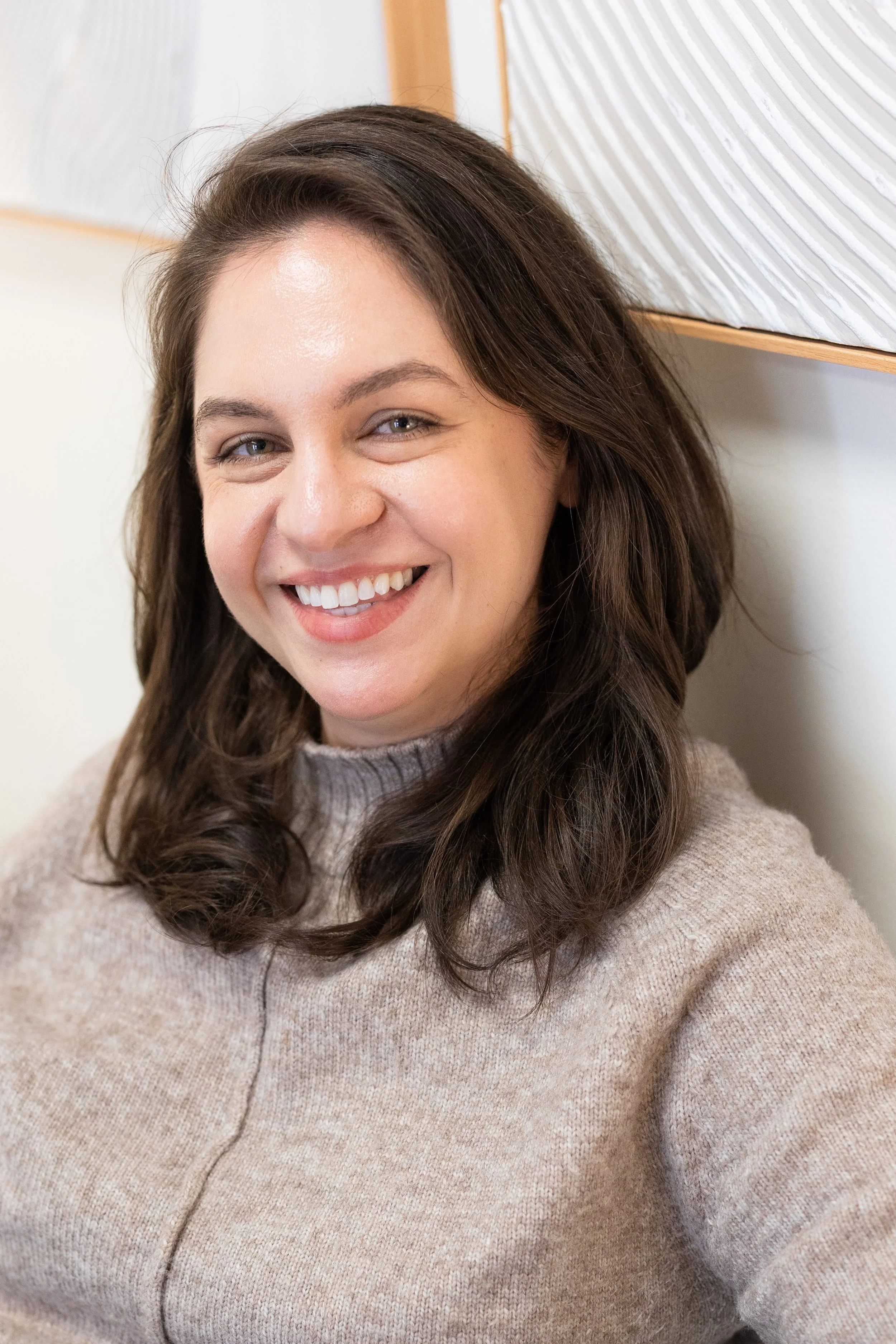 Therapist for anxiety in Bellevue, WA for high-functioning adults dealing with stress and burnout, smiling while sitting against a wall.