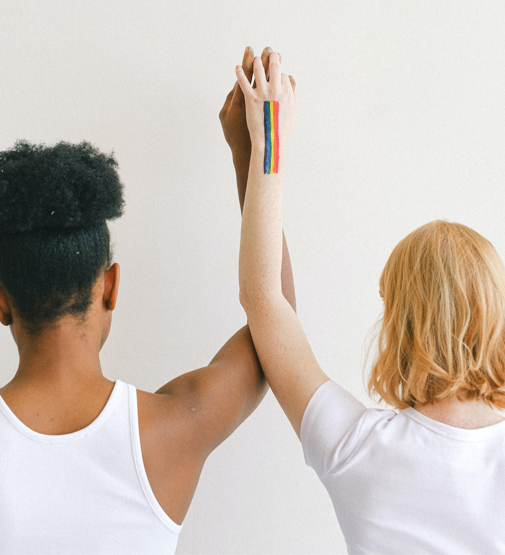 two people standing holding hands with a rainbow flag painted on one
