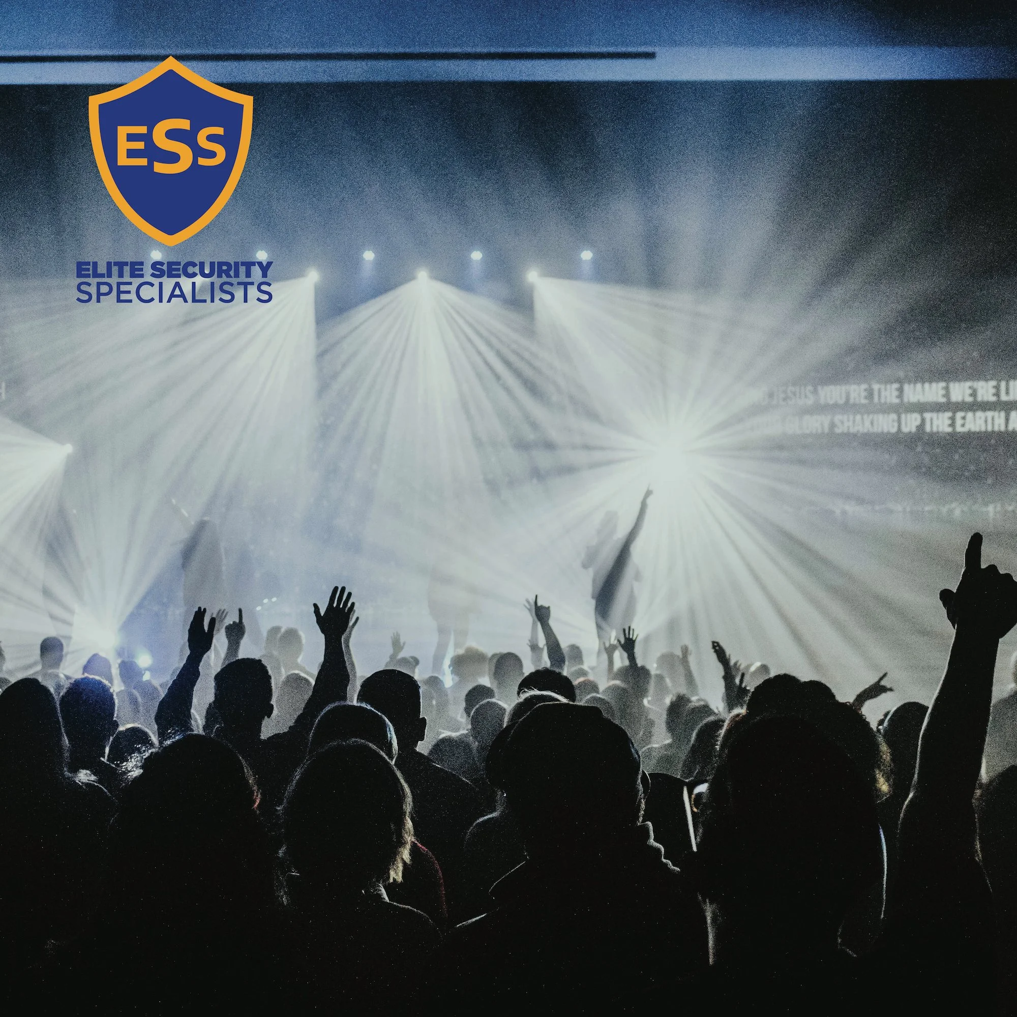 Crowd of people at a concert or event with bright lights and spotlights in the background, and a logo in the top left corner that reads 'ESS' with the text 'Elite Security Specialists' beneath it.