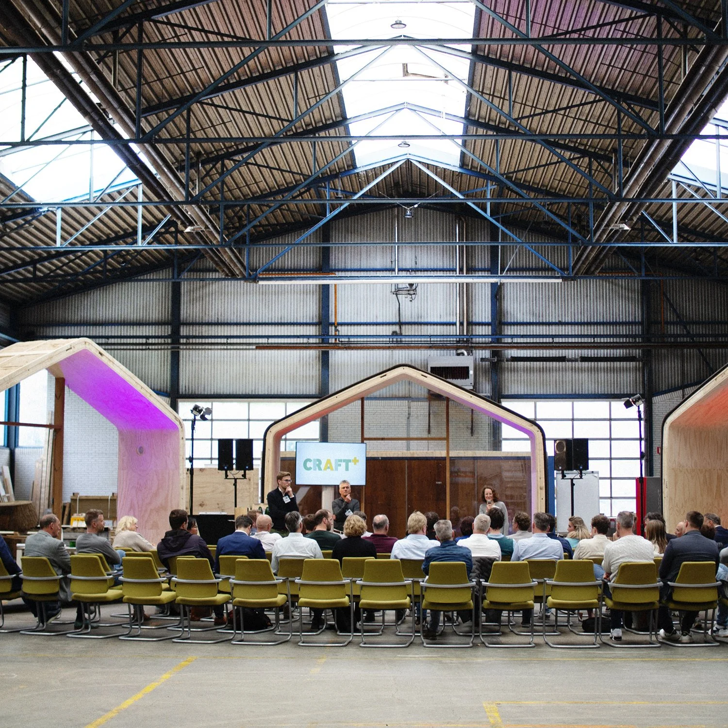 Een conferentie of presentatie in een grote industriële ruimte met een houten en metalen plafond. Evenement lokatie Friesland NijeLeije