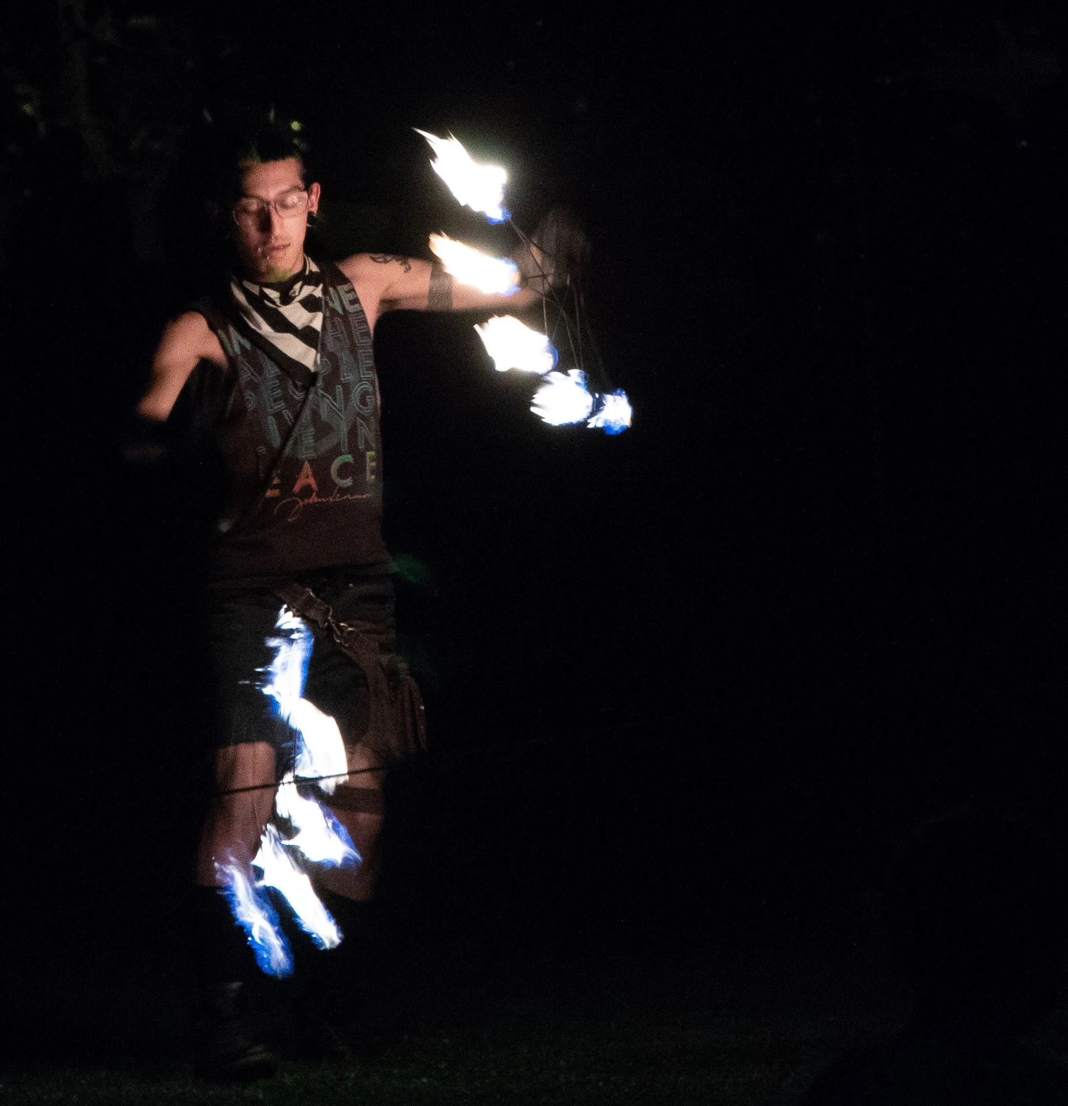 Person performing fire breathing at night with flames coming from their mouth.