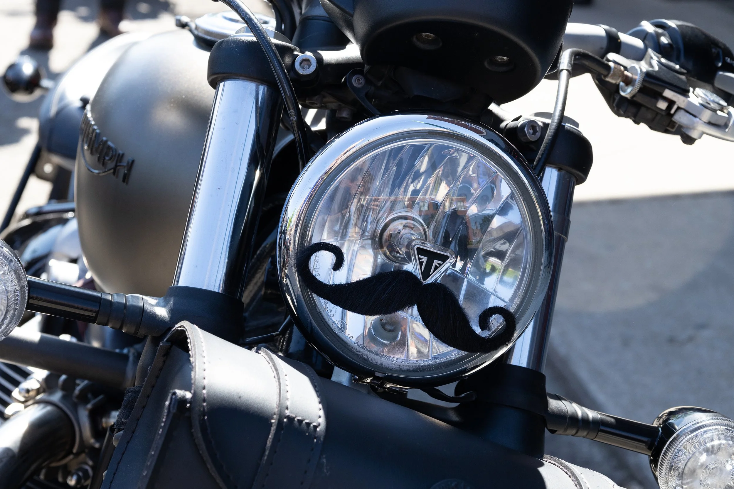 Close-up of a motorcycle's front headlight and handlebars, with a gray fuel tank and black accents.