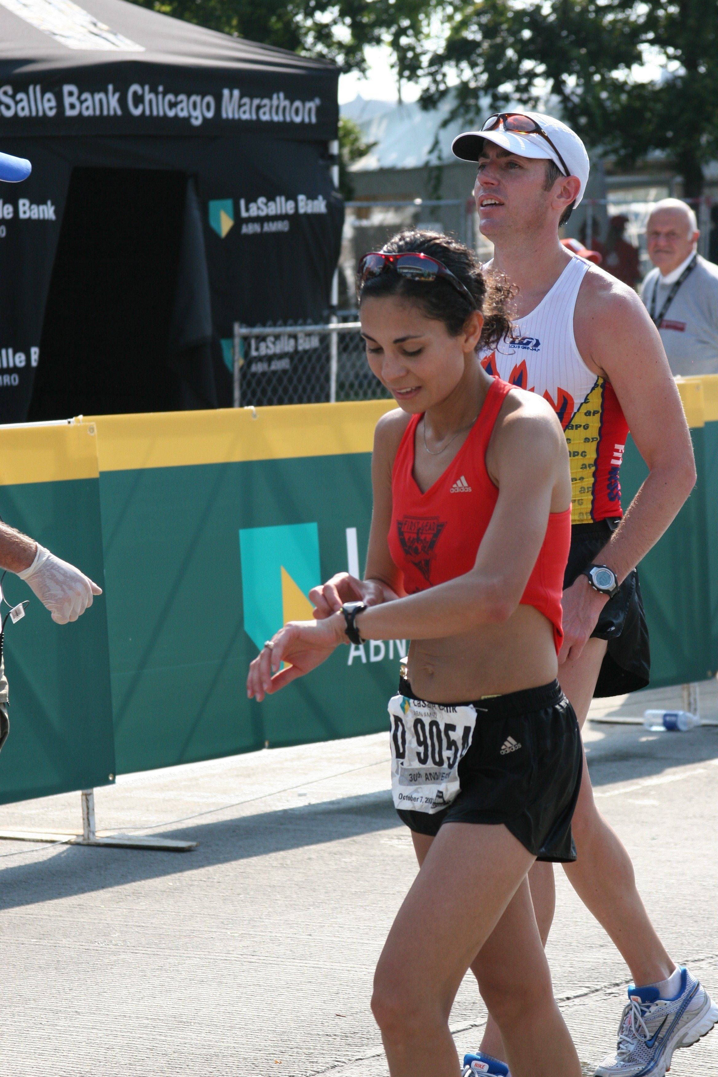 A male and female marathon runners crossing the finish line at the Chicago Marathon, with a banner behind them reading 'LaSalle Bank Chicago Marathon'.