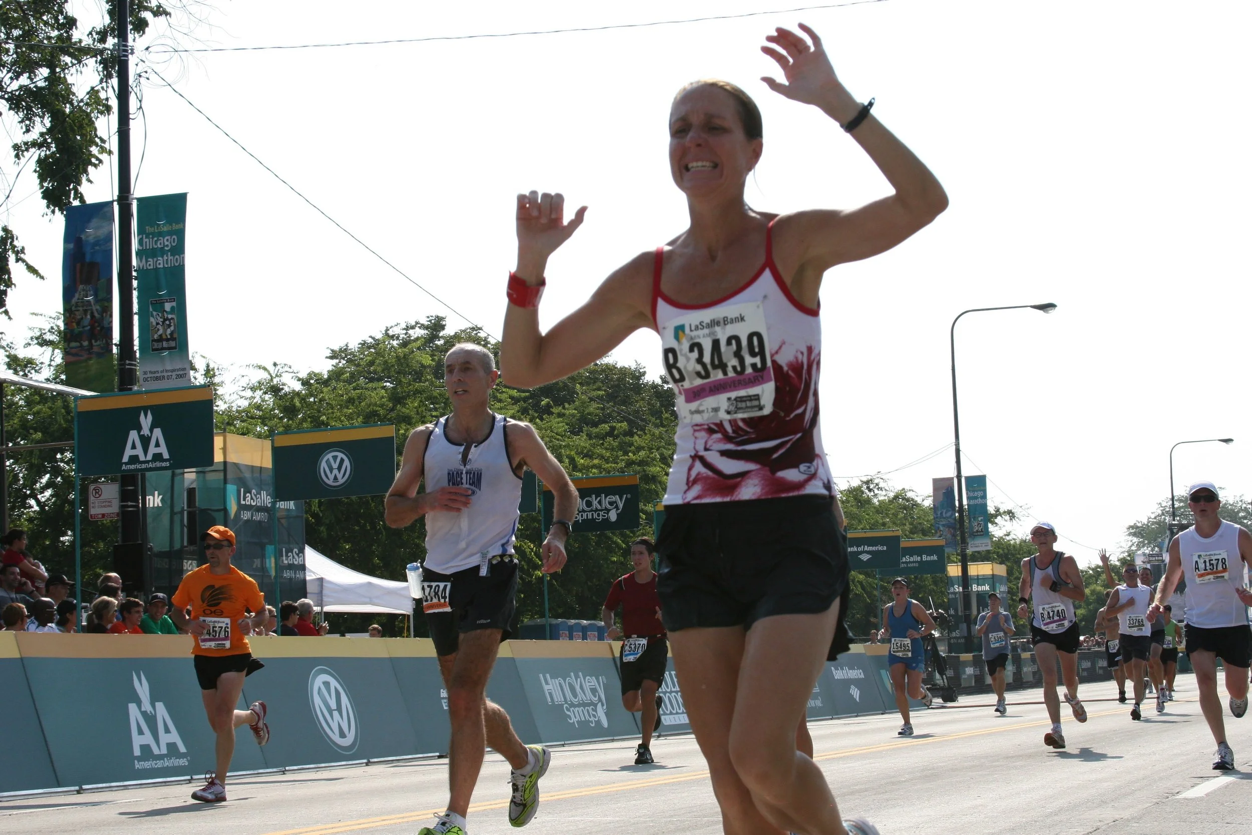 Race start at the Chicago Marathon with marathon runners crossing the finish line, cheering crowds, and event banners in the background.