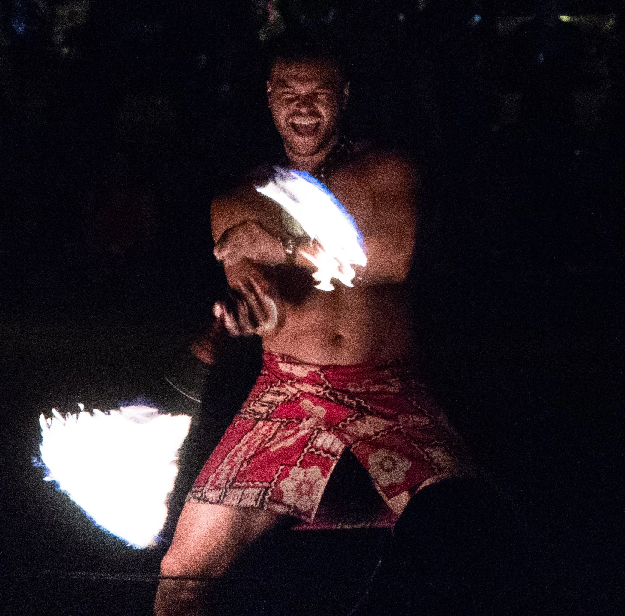 A person at night holding a firework, smiling and appearing excited, with stars visible in the dark sky background.