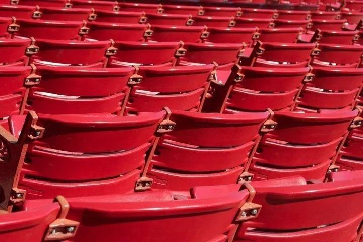 A large number of empty red stadium seats arranged in rows.