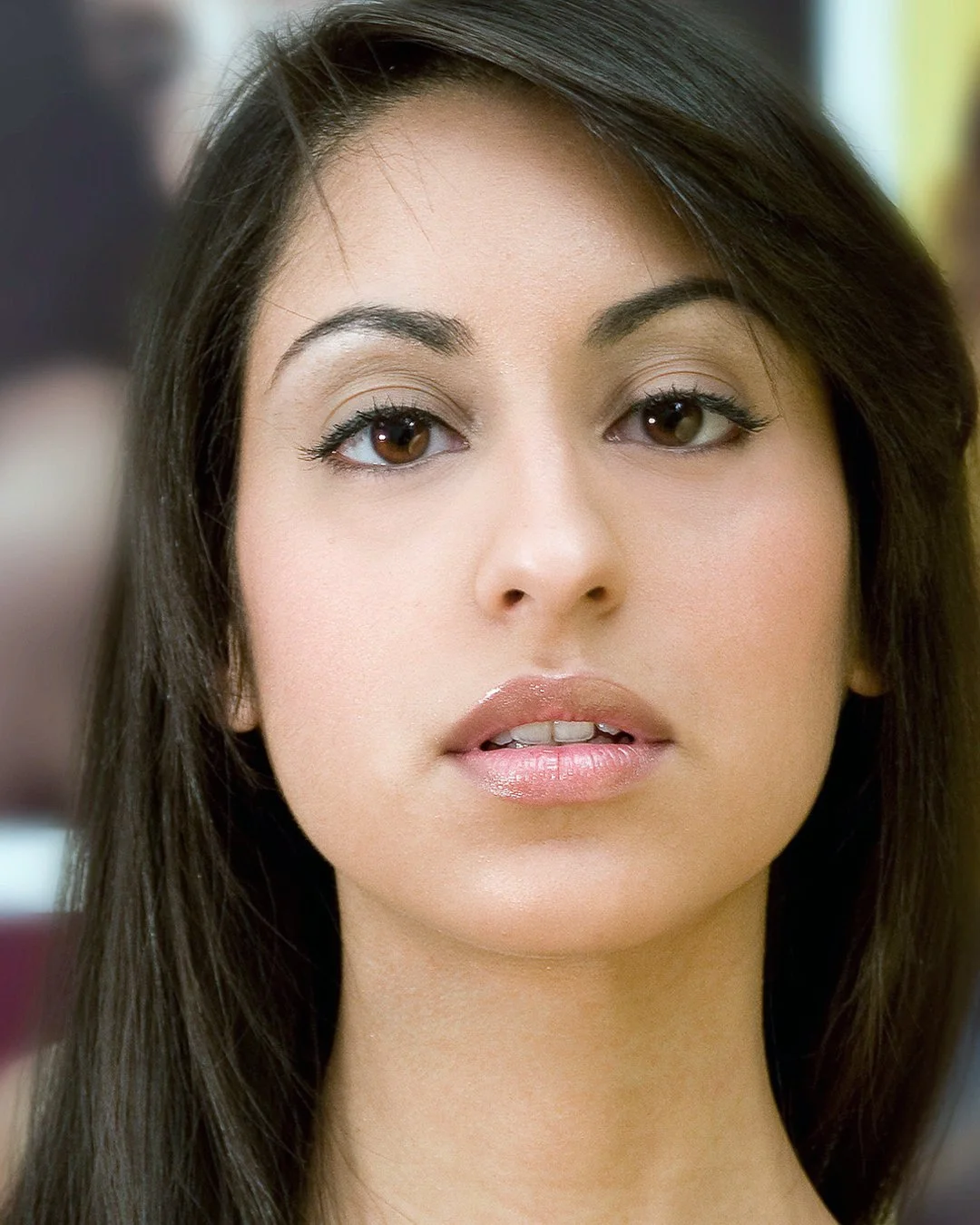 Close-up of a woman with dark hair and brown eyes, looking slightly to the side.