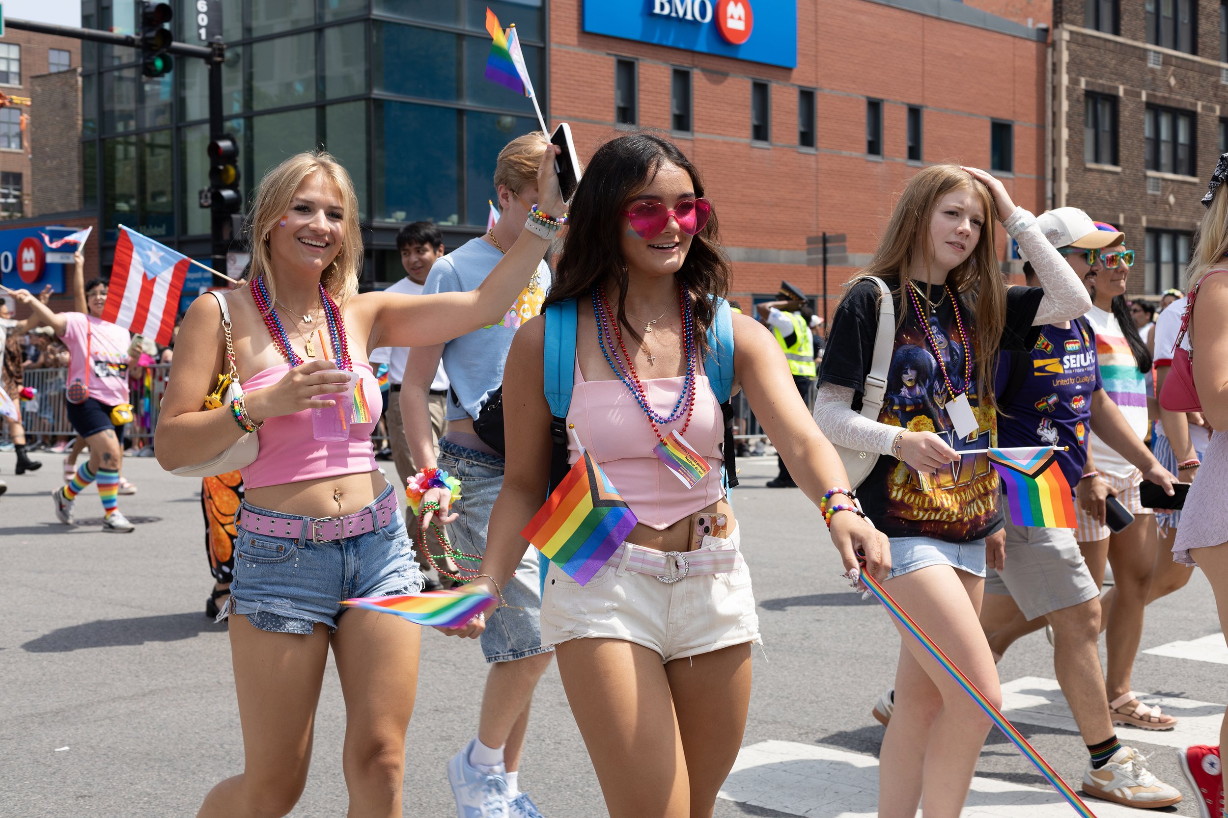 Group of people celebrating at a pride parade, holding rainbow flags and wearing colorful accessories.