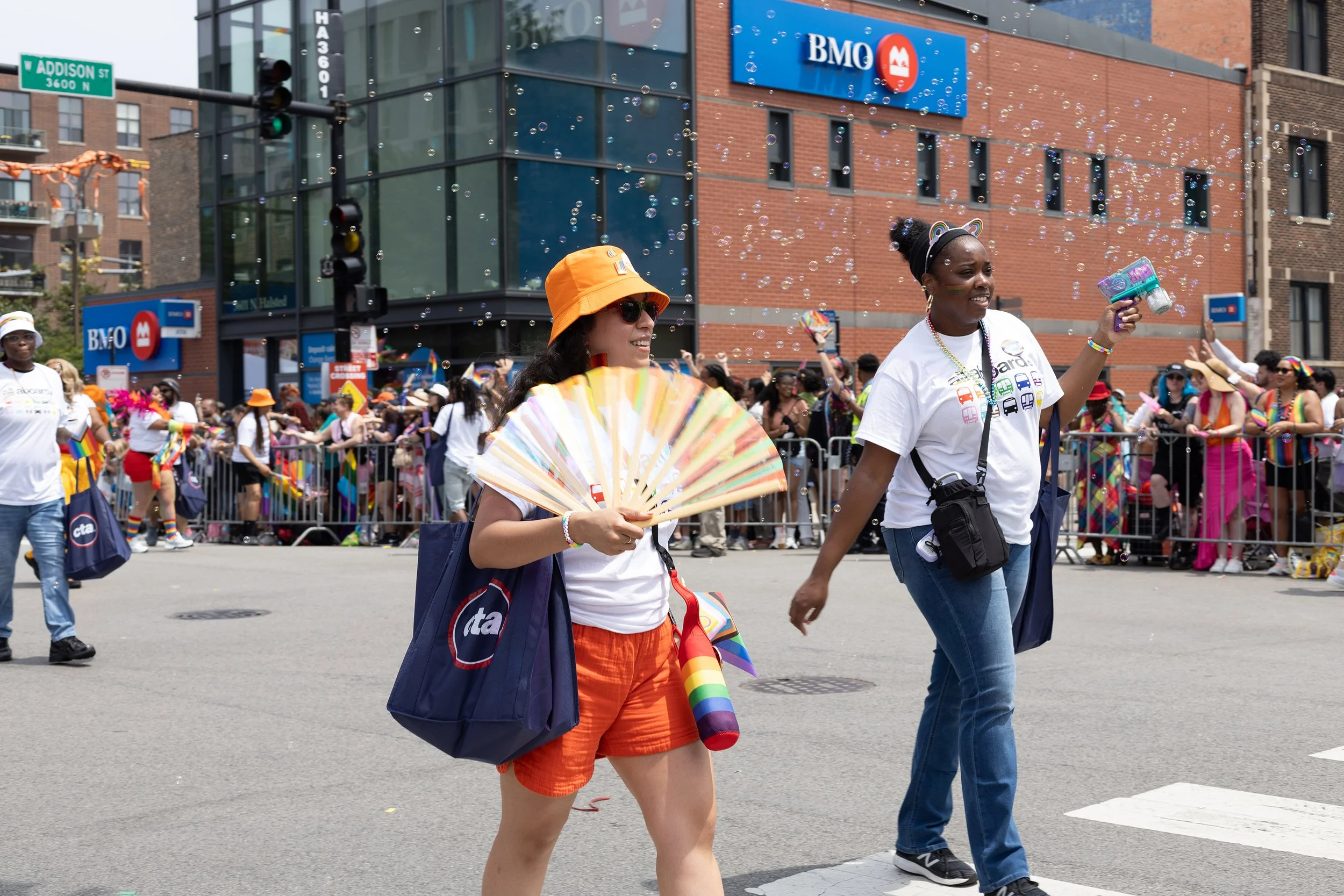 People participating in a Pride parade on a city street, with rainbow flags and festive attire, celebrating diversity and LGBTQ+ pride.