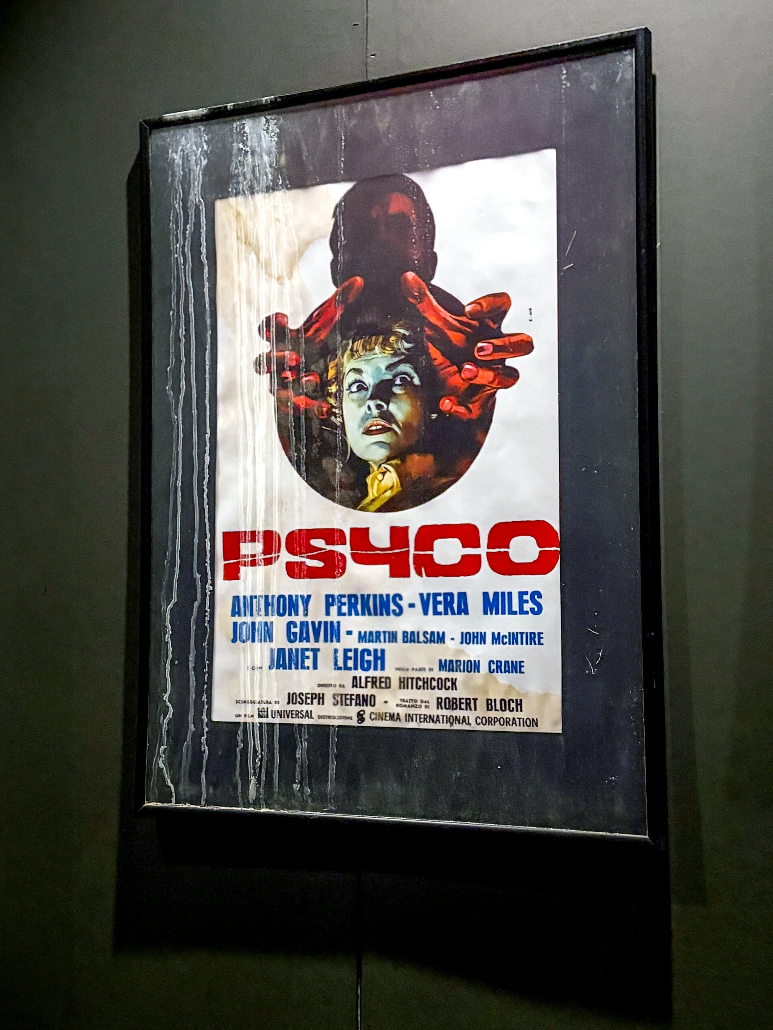 Framed vintage movie poster for 'Psycho' with images of a woman and a skull-like face, featuring a list of cast and crew members.
