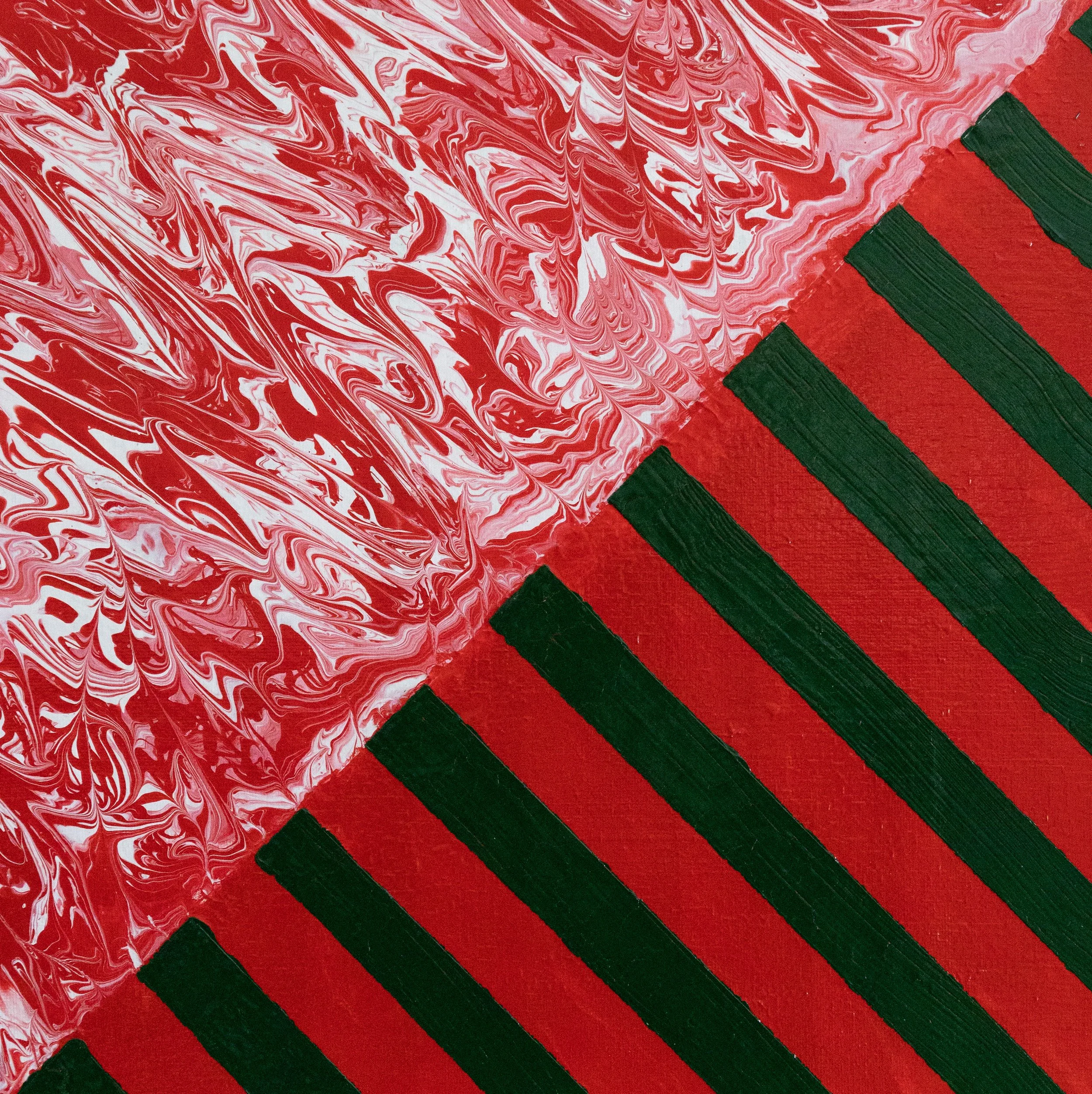 Close-up of a red, green, and white marbled surface next to a red surface with green diagonal stripes.