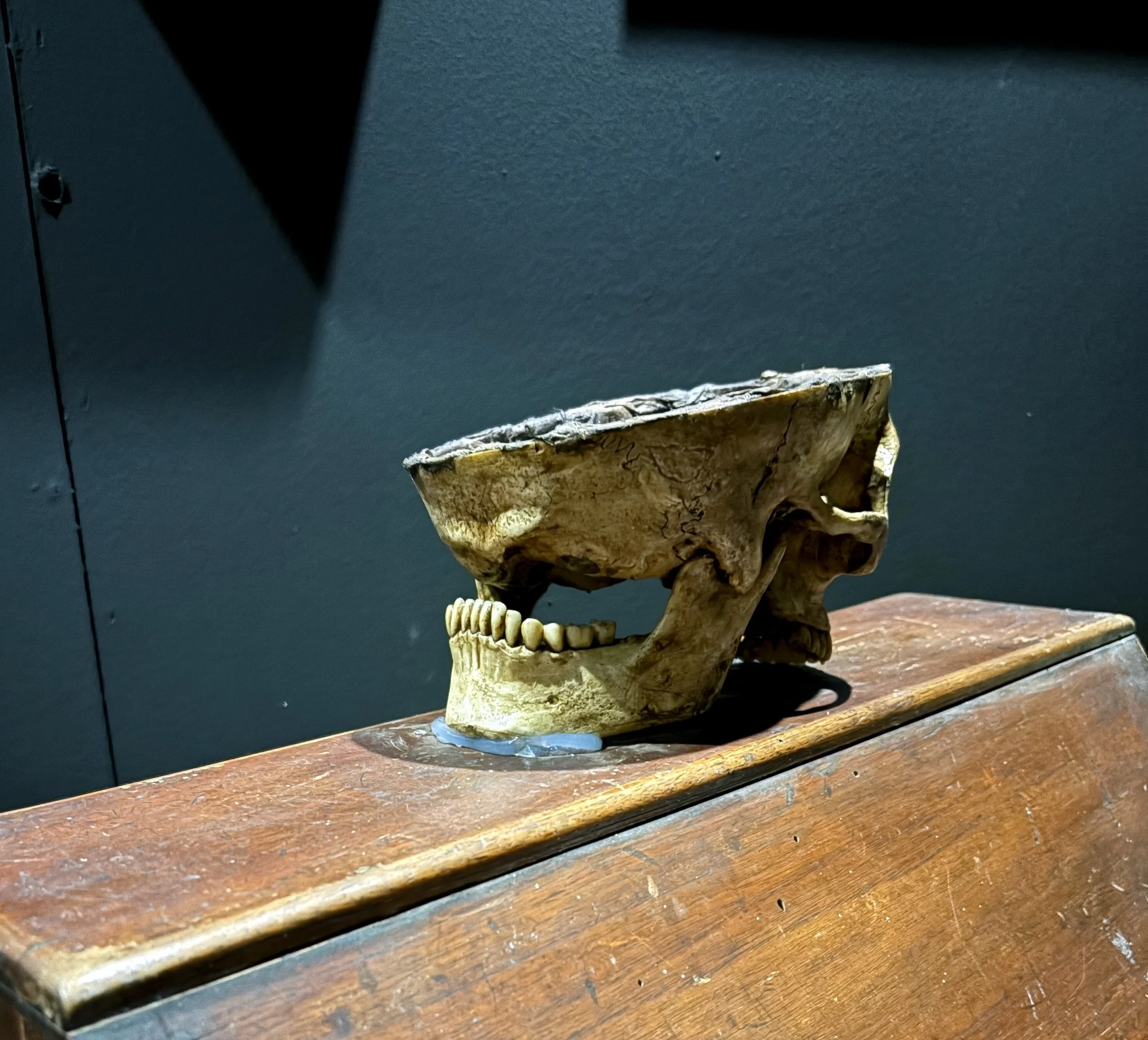 A volcanic rock sculpture resembling a skull, displayed on a wooden surface against a dark background.