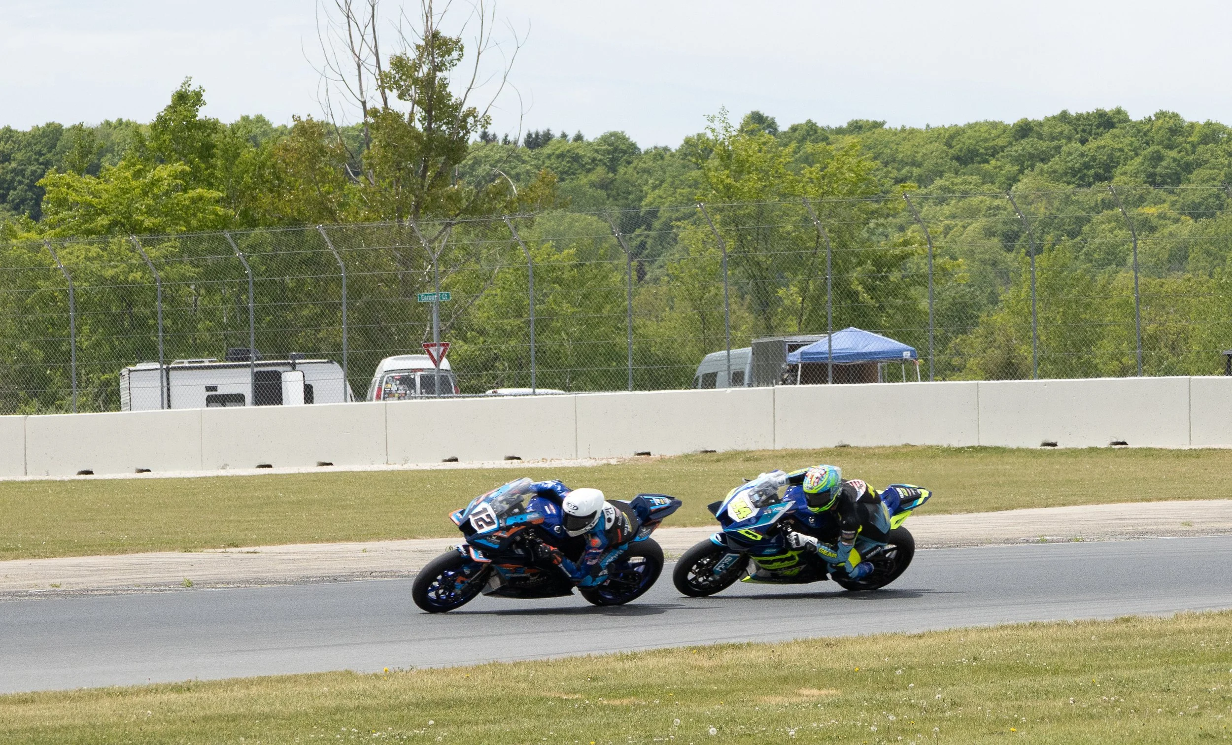 Two motorcycle racers leaning into a turn on a racetrack during a race.