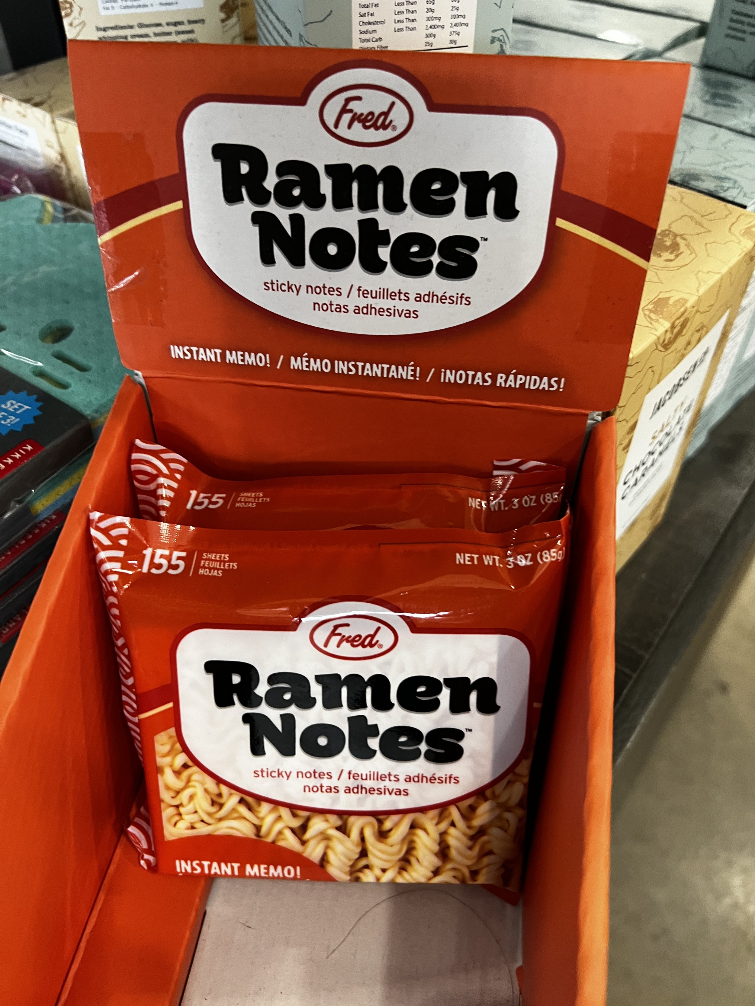 A red box of Fred Ramen Notes sticky notes, with a clear window showing beige ramen noodle print on the sticky notes inside.