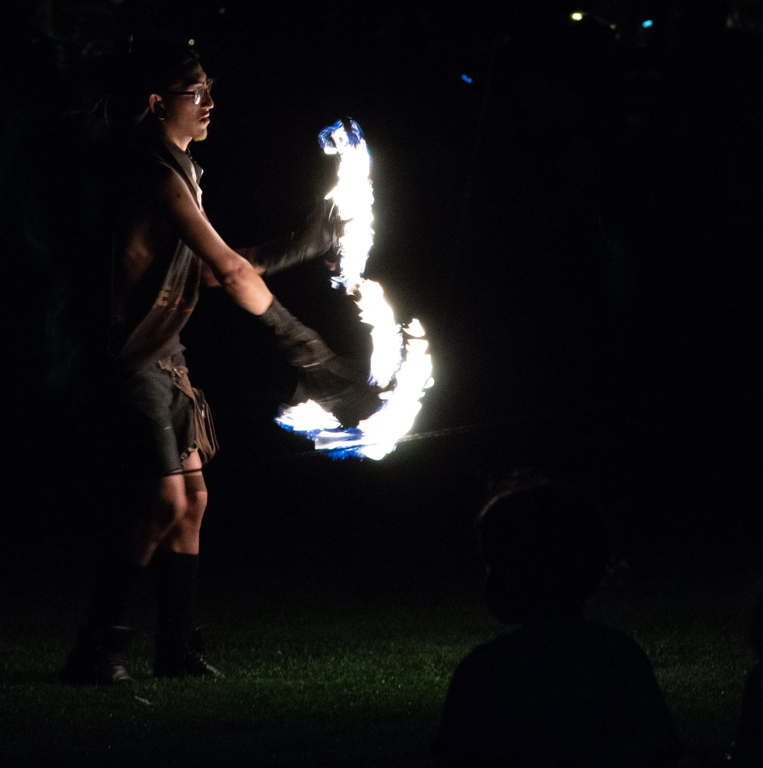 Person playing with fire on a night outdoors, with a ring of flame and sparks visible in the dark.