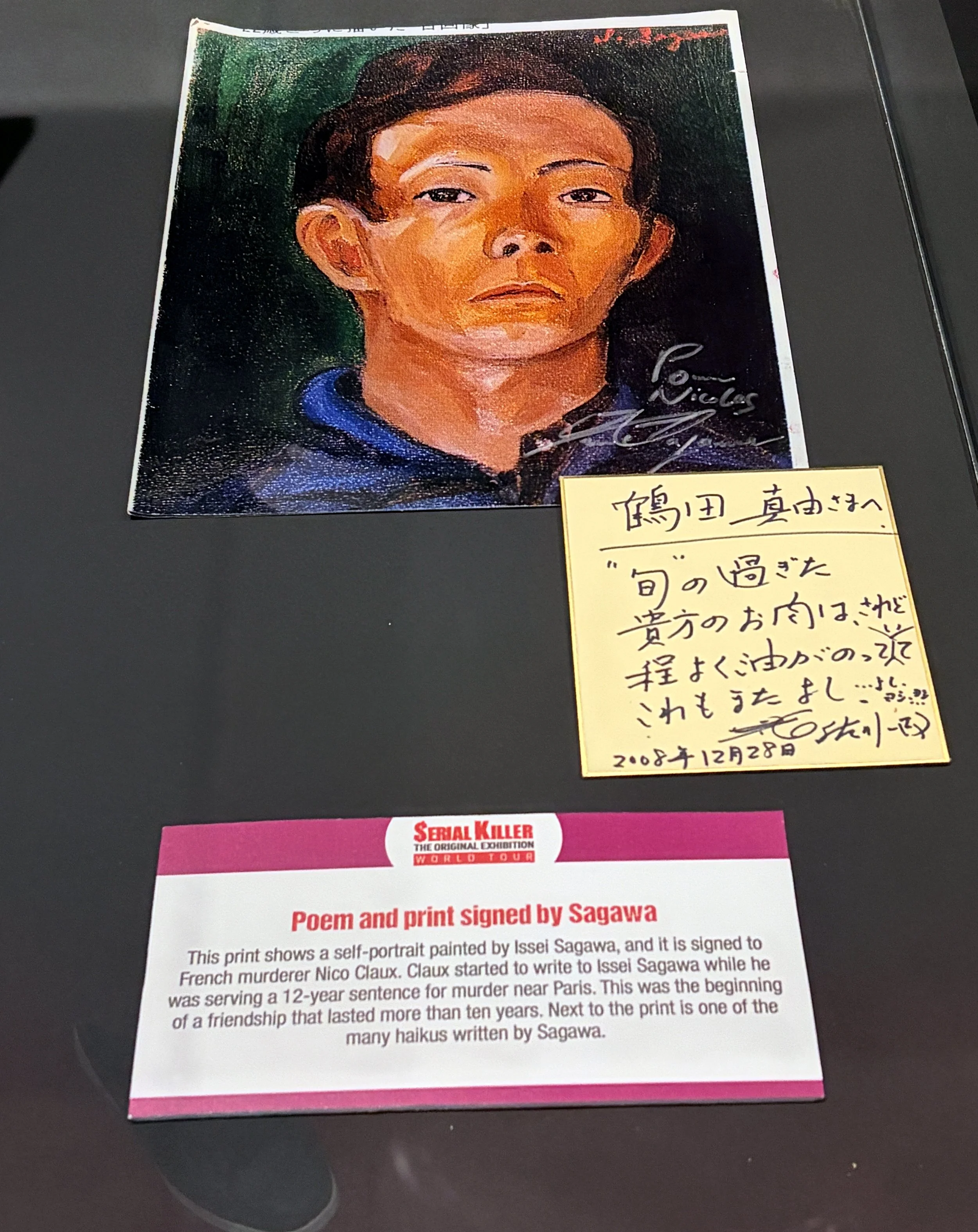 A self-portrait painting by Issel Sagawa, signed by the artist, depicts a serious-looking person with short hair. The painting is displayed on a black surface. Below the painting, there's a message explaining the artwork's background, including its c