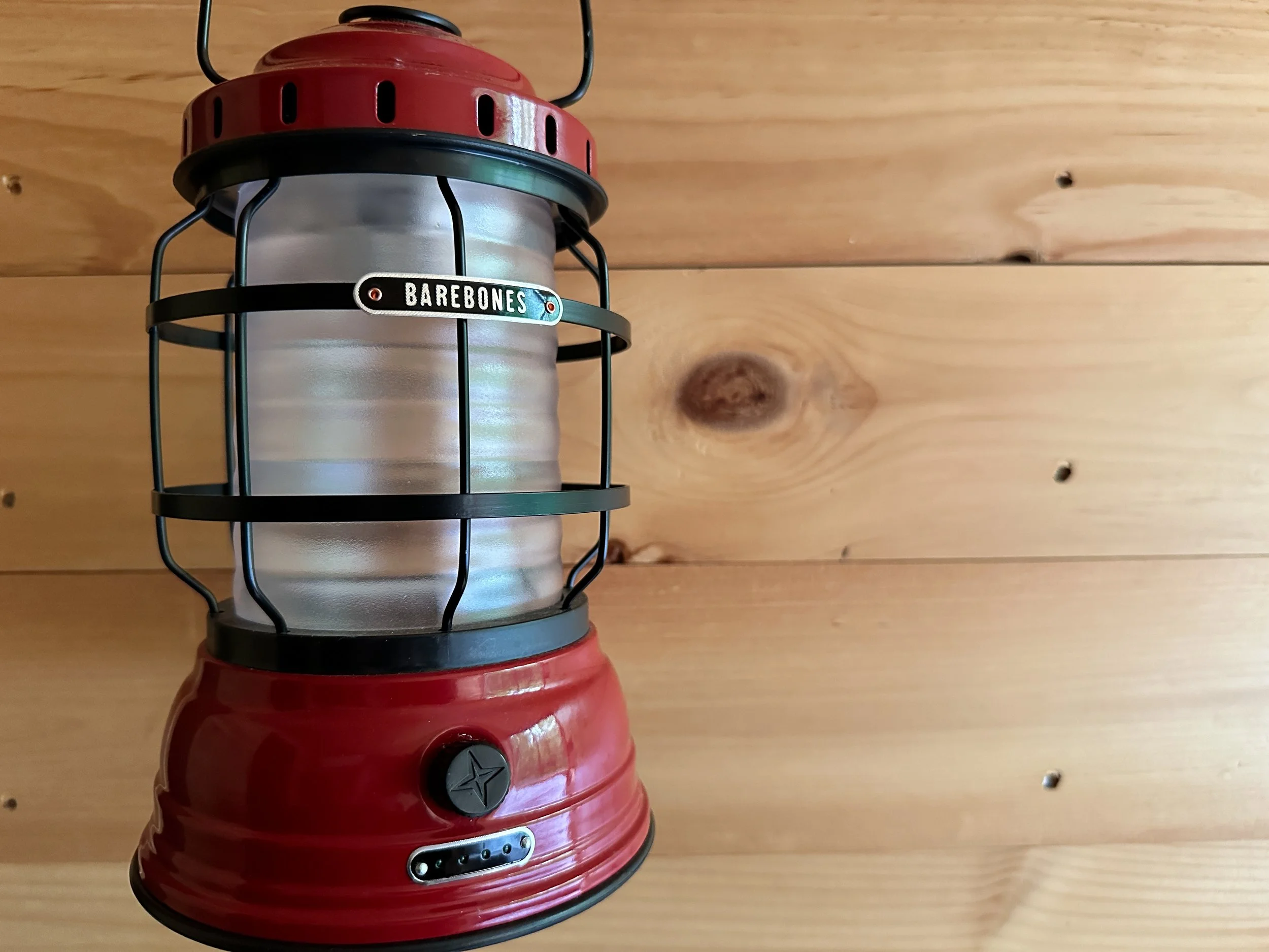 Red vintage Coleman lantern mounted on a wooden wall.