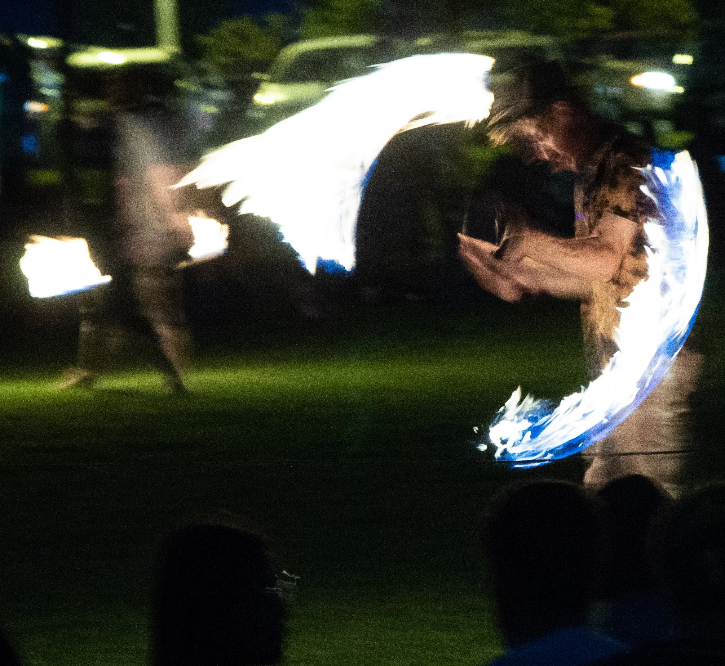 A blurry image of a nighttime scene with a bright white and blue globe reflecting on a surface, surrounded by dark and indistinct shapes.