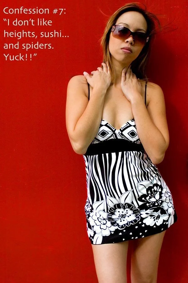 A woman wearing sunglasses and a black and white patterned dress stands against a red wall, with her arms crossed near her neck. Text in the image reads: "Confession #7: 'I don't like heights, sushi... and spiders. Yuck!!'"