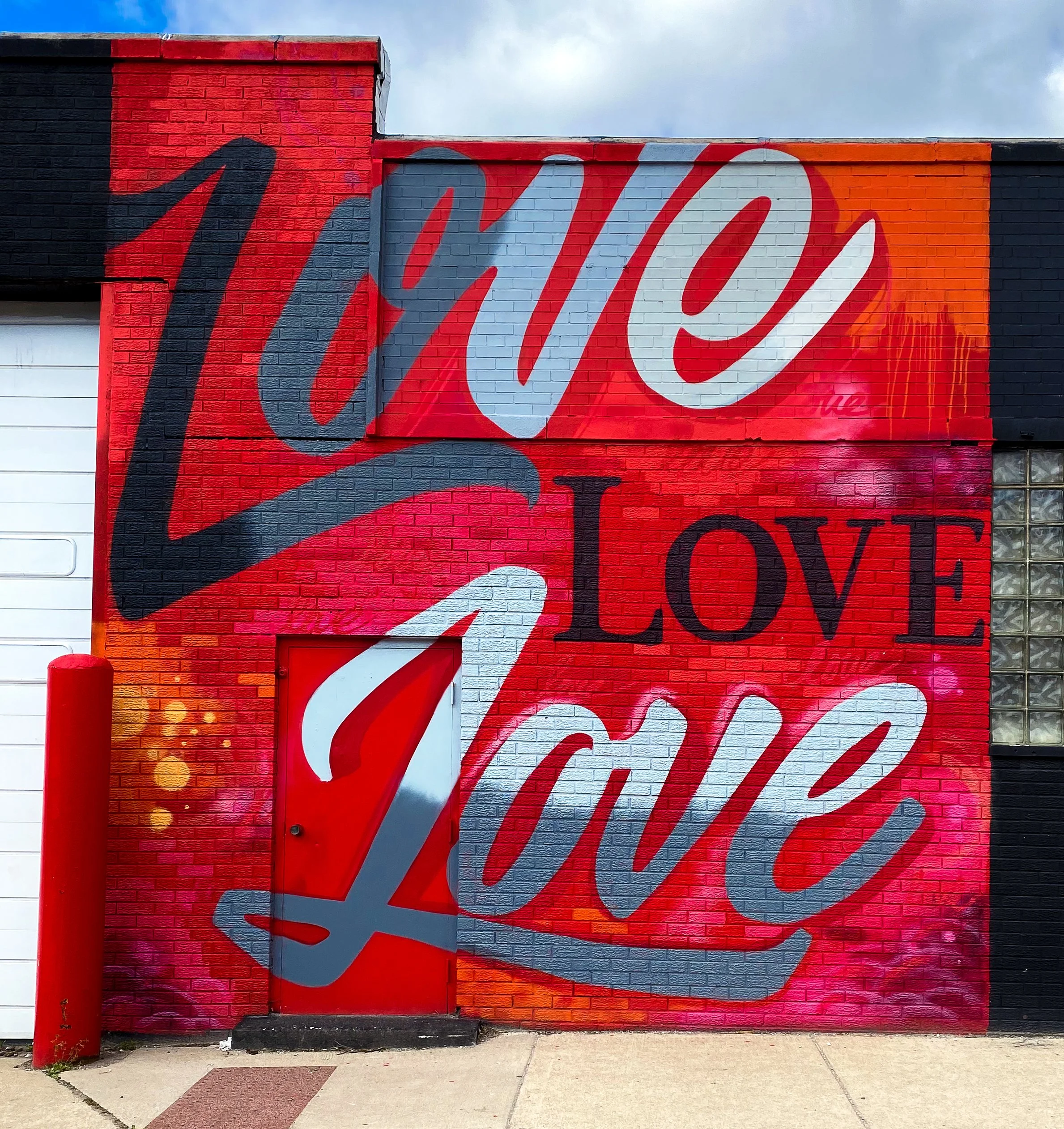 Colorful mural on a brick wall with large cursive text in red, white, black, and blue paint.