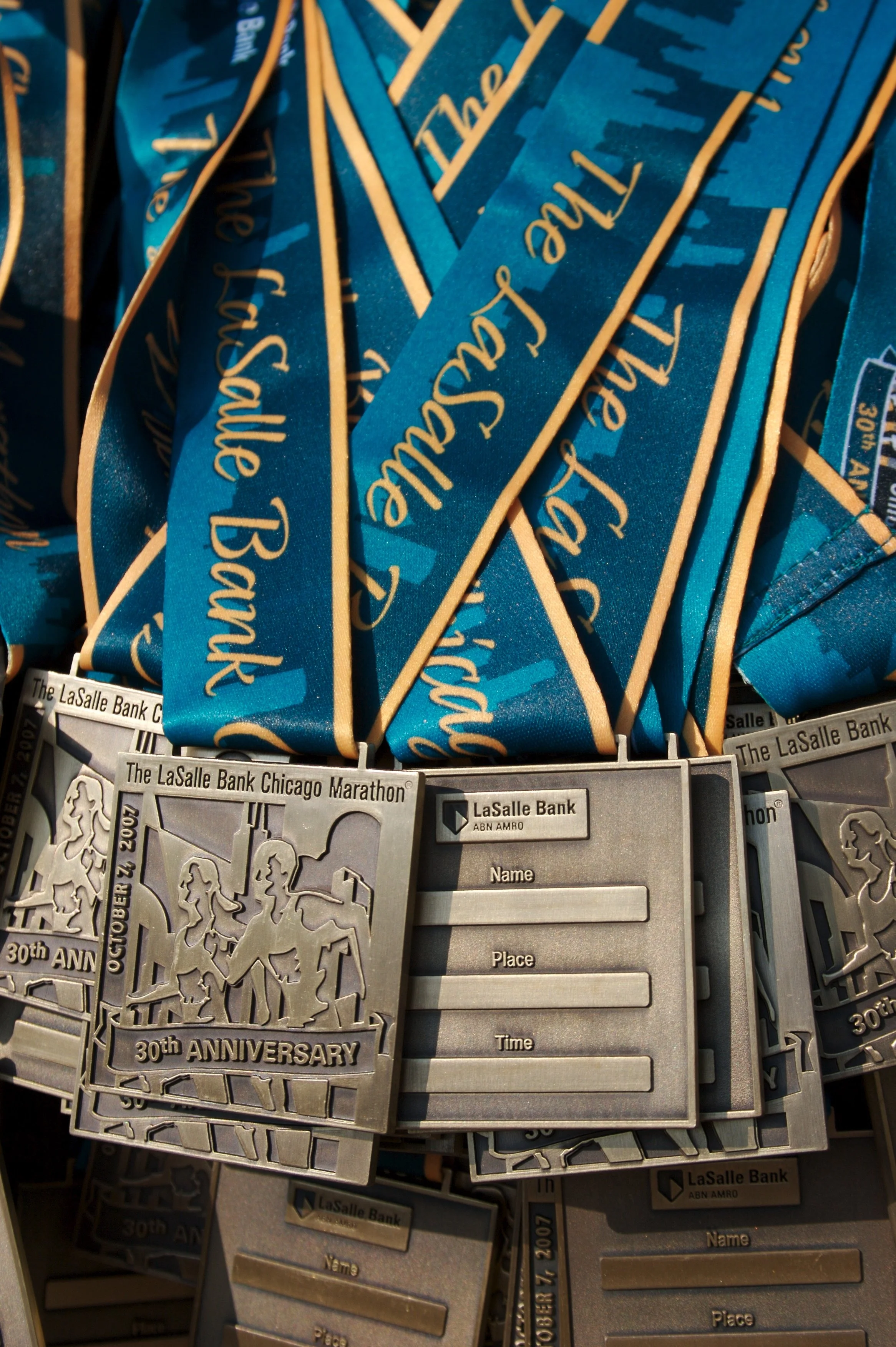 Multiple blue and gold ribbons with the phrase 'The Greatest Boston Sausage' and metal medals with a running event map for the 30th Anniversary of the LaSalle Bank Chicago Marathon.