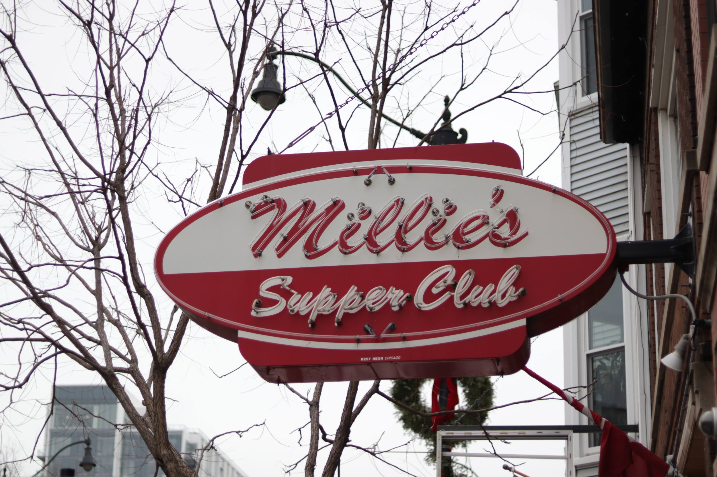 A red and white oval sign for McDonald's Superior Club hangs outside a building, with leafless trees and a street lamp visible in the background.