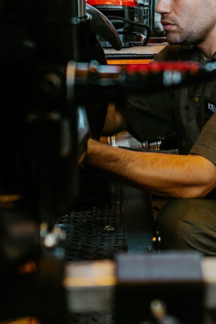 Homem trabalhando em uma máquina industrial ou mecânica, focado na manutenção ou reparo.