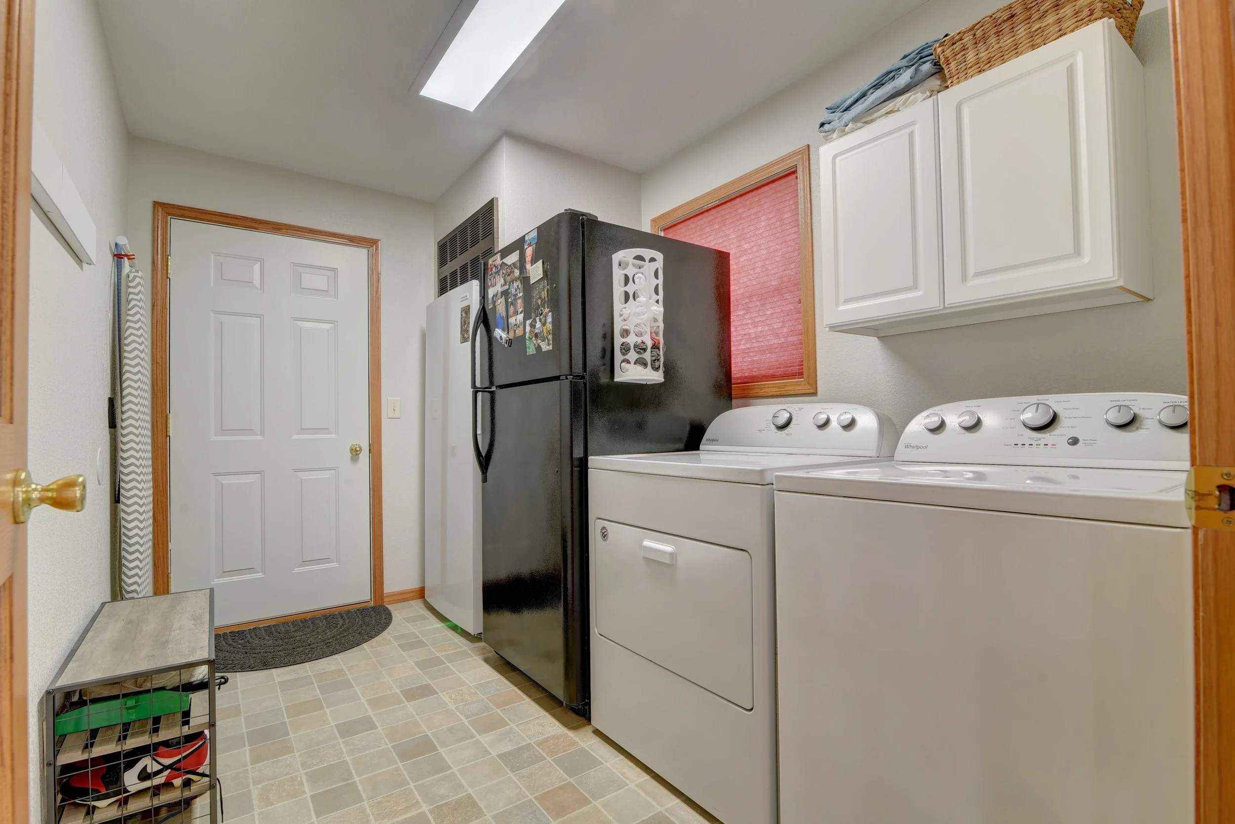 Laundry room with white cabinets, black refrigerator, washing machine, and dryer.