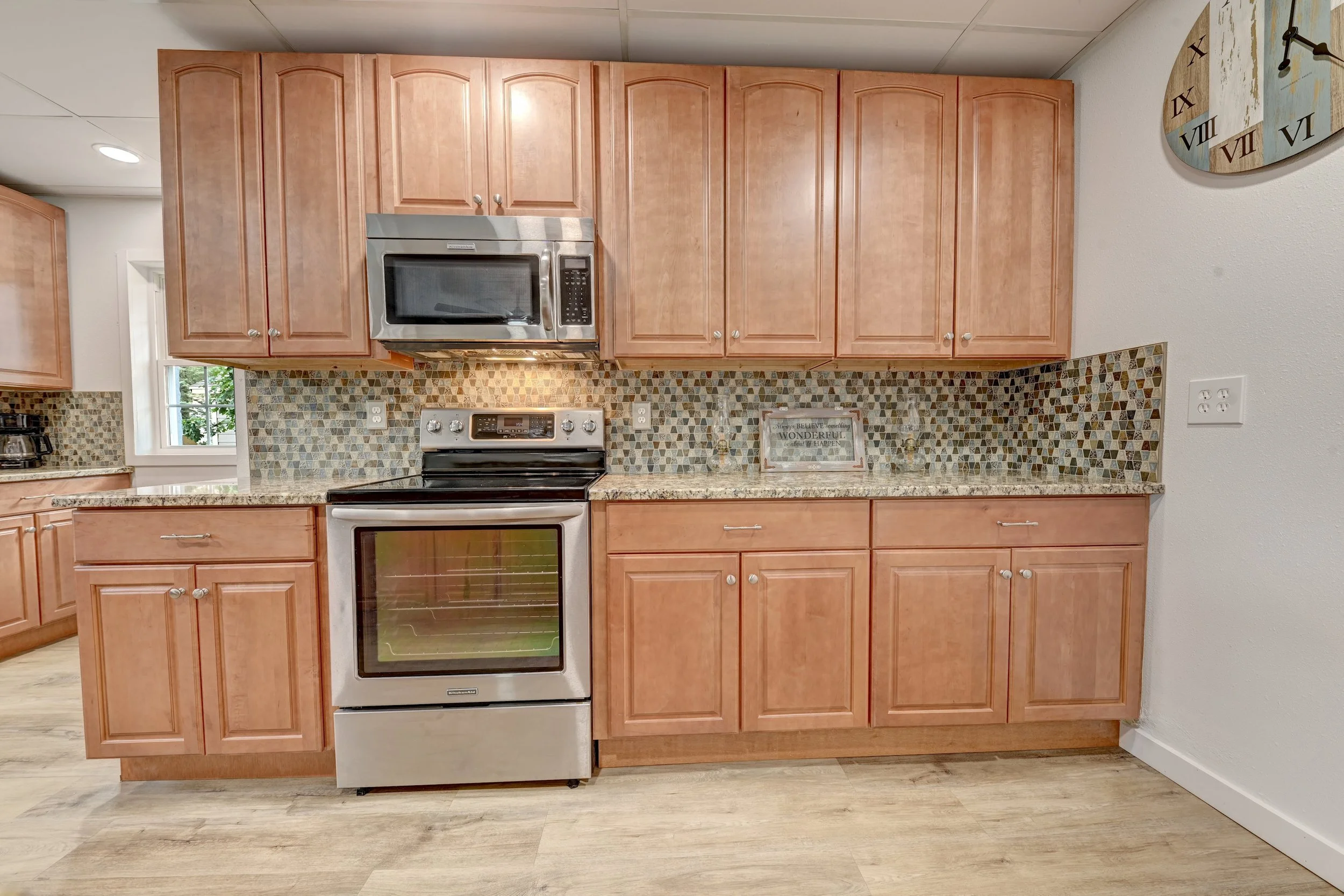 Kitchen with wooden cabinets, stainless steel microwave oven, stove, and decorative tile backsplash.