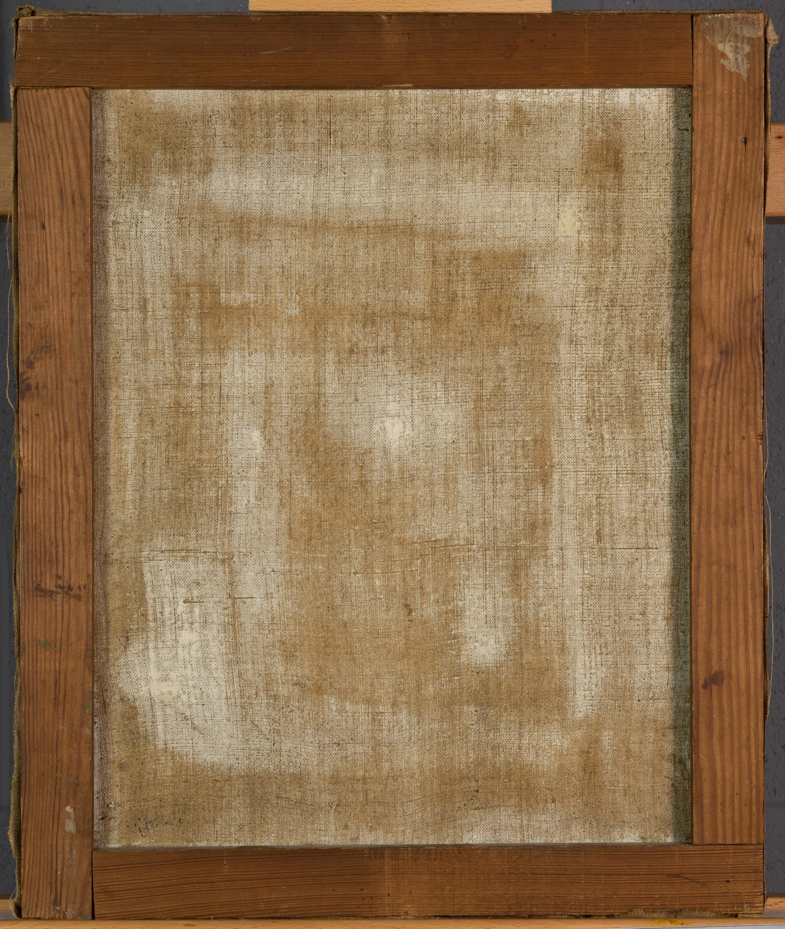 Backside of a painting on canvas on a wooden strainer. The strainer consists of four pieces of wood secured together at the corners to form a rectangle, like a picture frame.