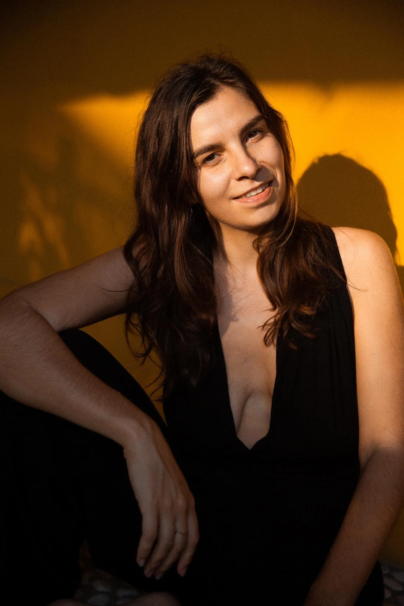 Woman sitting in front of orange wall sun shining onto her