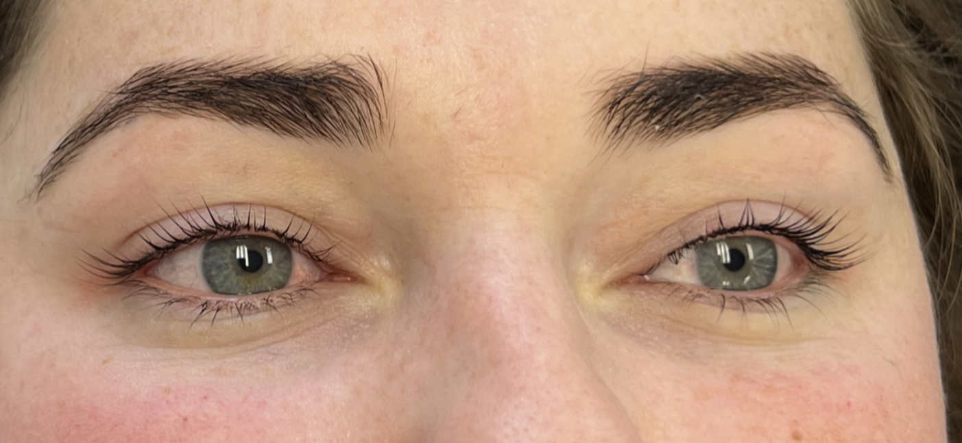 Close-up of a person's eyes with well-groomed eyebrows, light skin, and natural makeup.