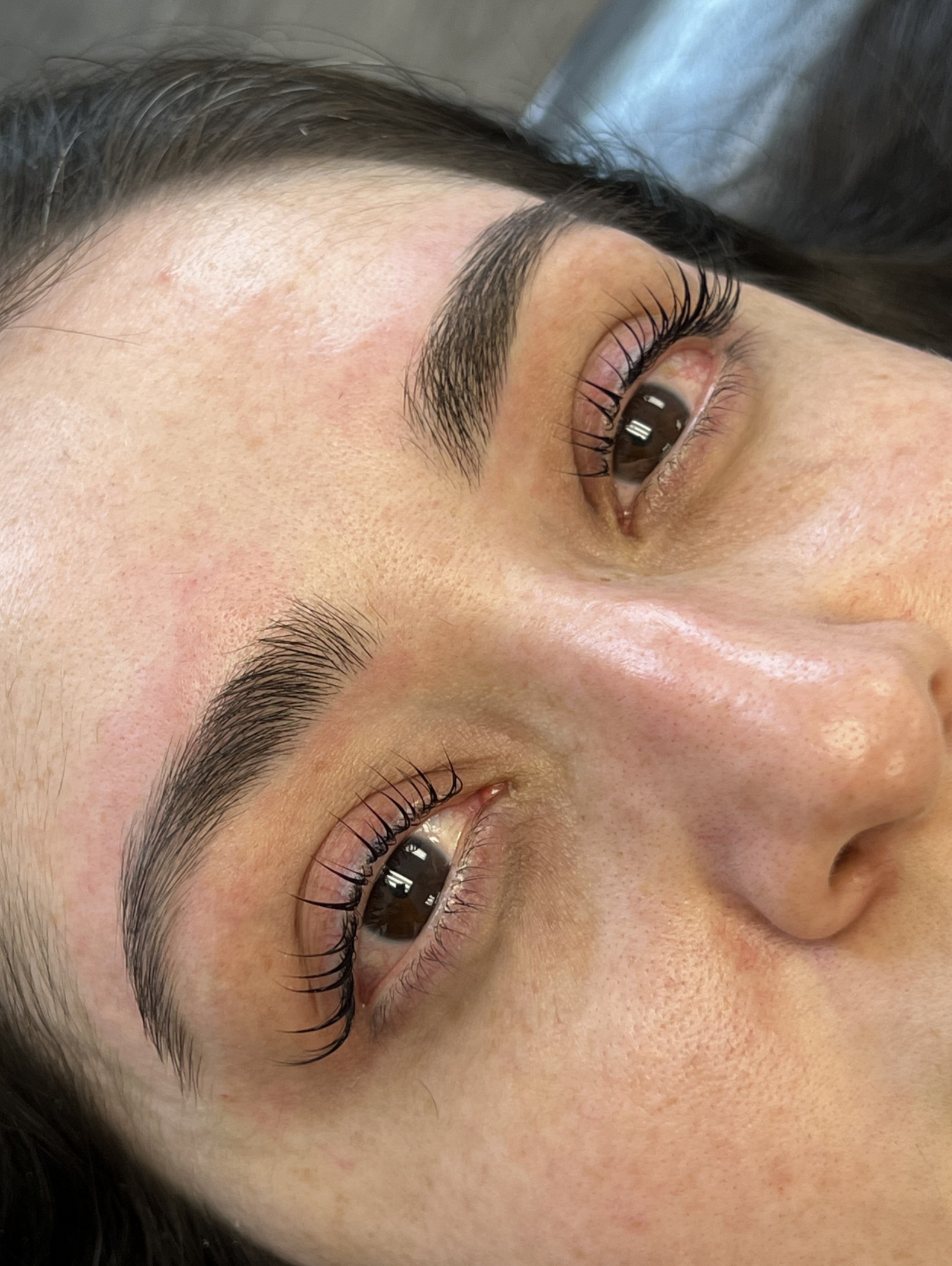 Close-up of a woman's face showing her eyes with a lash lift and tint and well-groomed eyebrows.