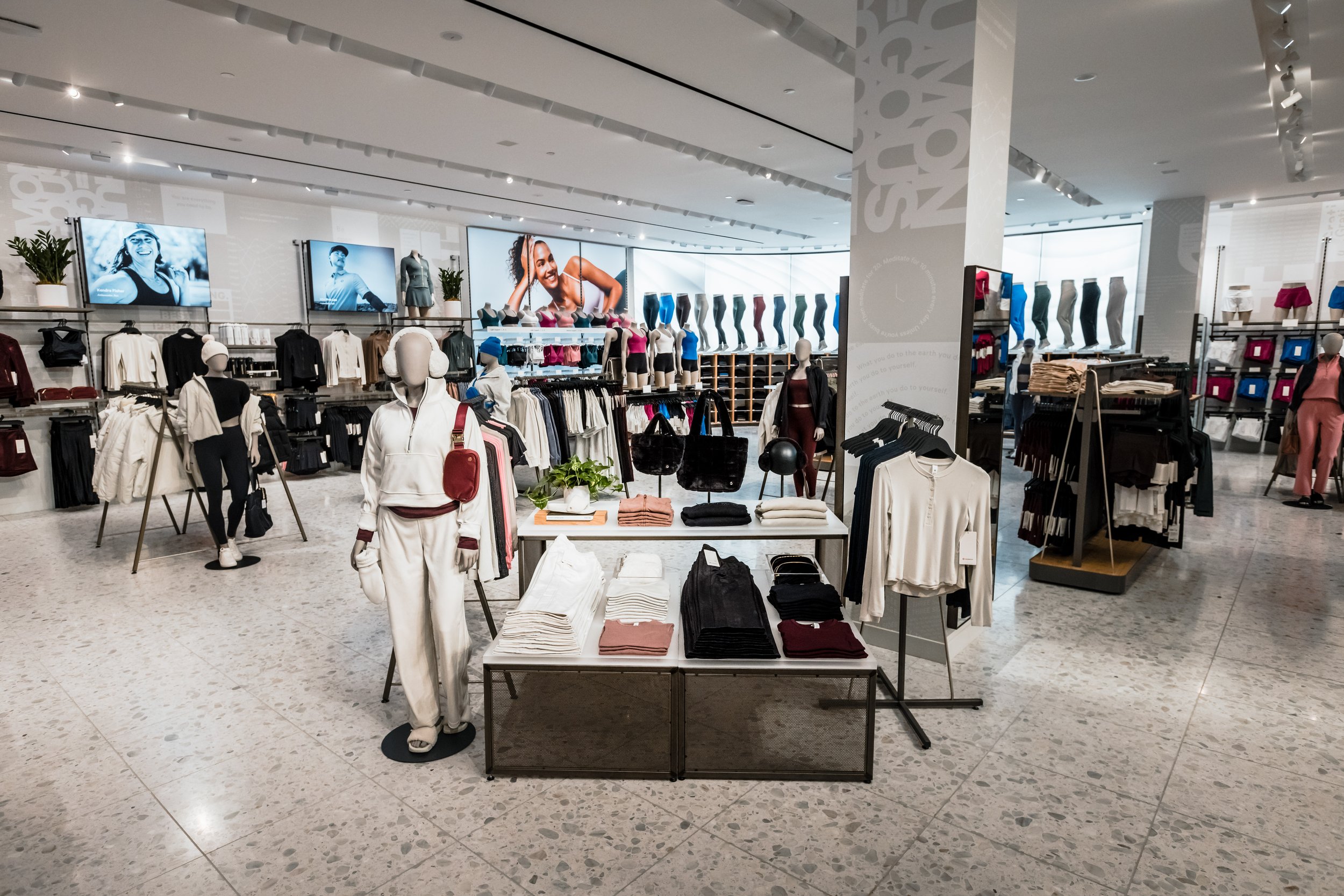 Interior of a clothing store with mannequins, racks of athletic apparel, and display tables.