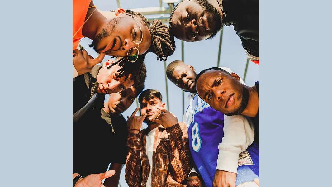 A group of eight young men looking down into the camera, taken from below with a clear sky background.