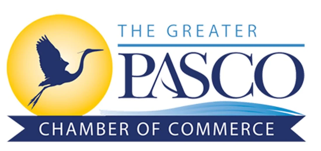 Logo of the Greater Pasco Chamber of Commerce featuring a heron in front of a yellow circle, with blue waves and text.