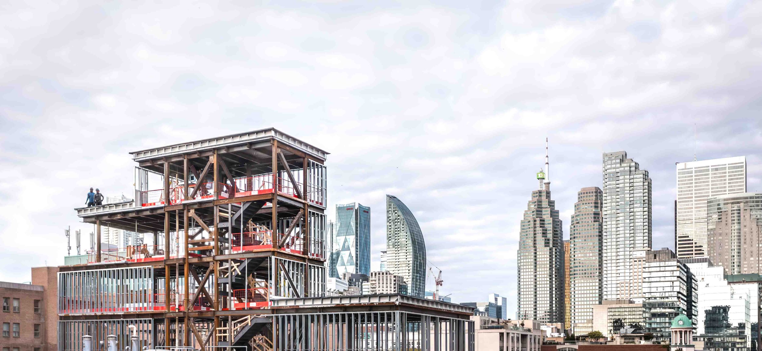 Urban construction site with partially completed building framework against a city skyline backdrop