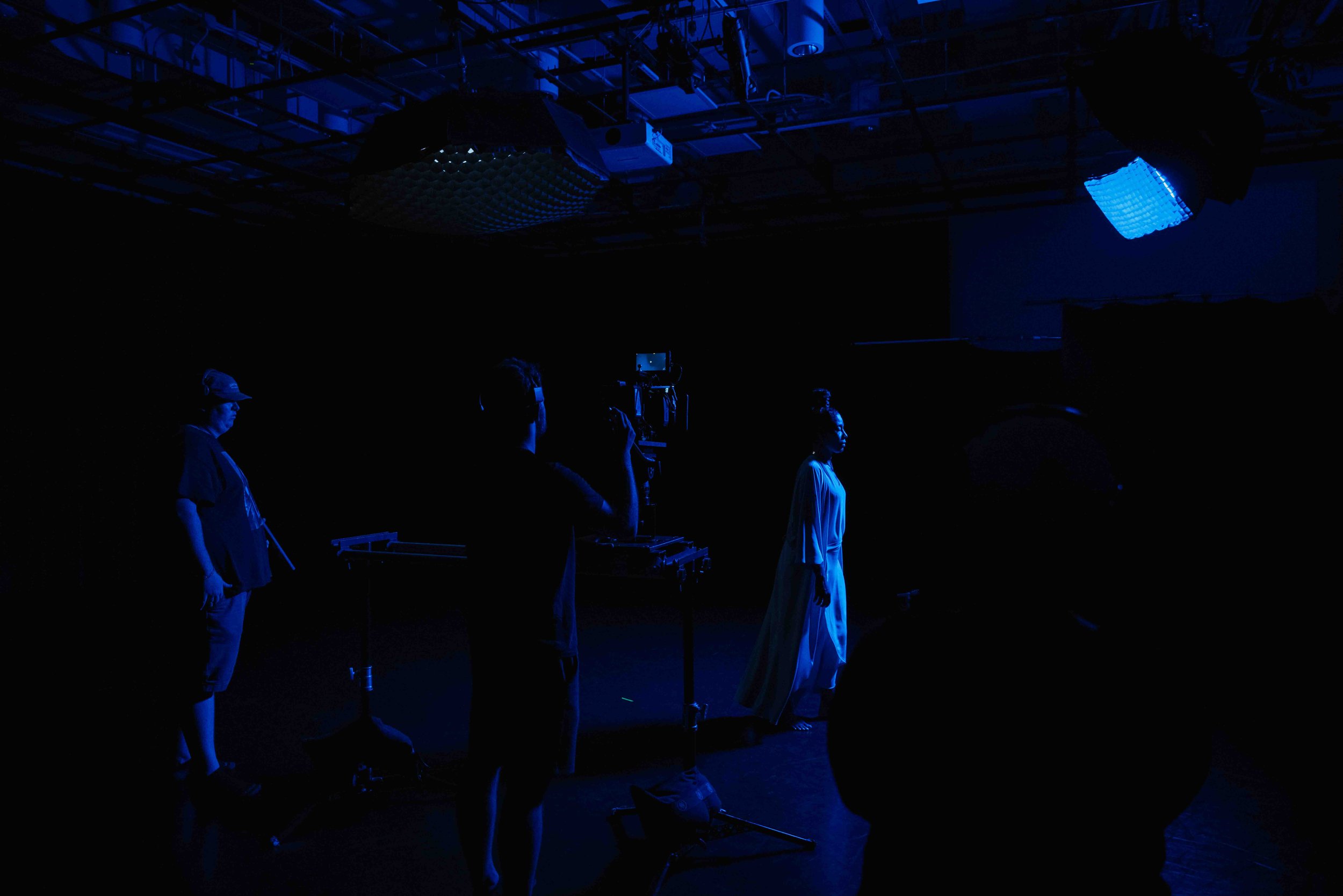 Film crew working on a dark blue-lit set