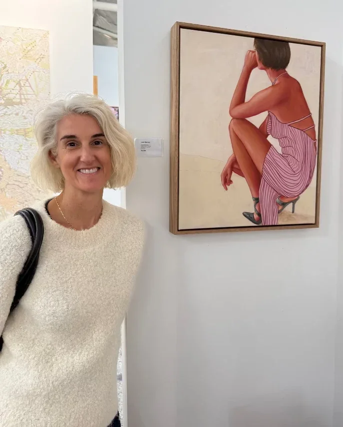 Artist_Leah_Mariani_with_leaderboard_painting_in_gallery.webp
