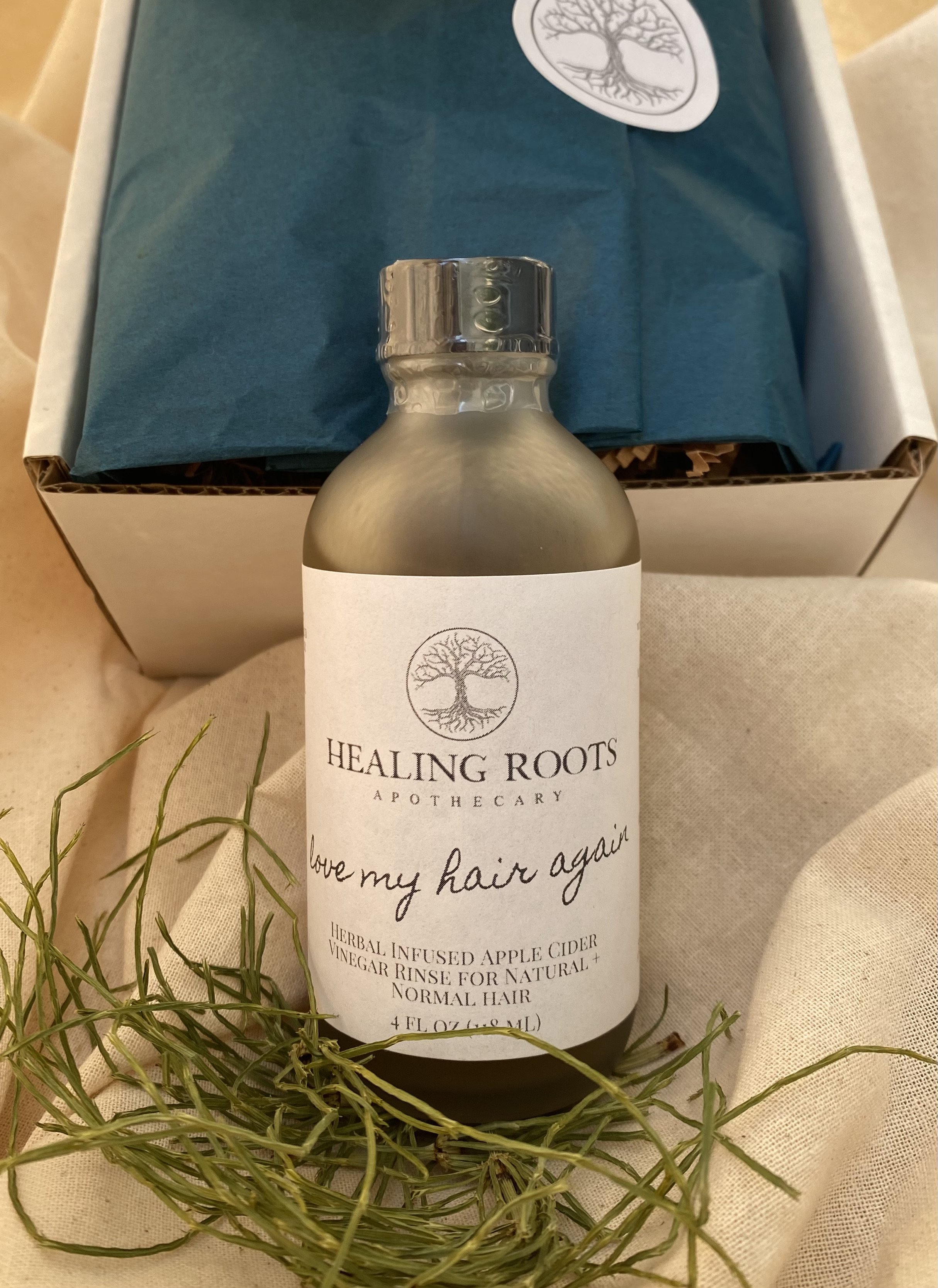 Rinses are carefully packaged in a flip top box. Lining the interior of the box is peacock blue wrapping paper adorned with a circular sticker with the tree of life logo printed on it.
