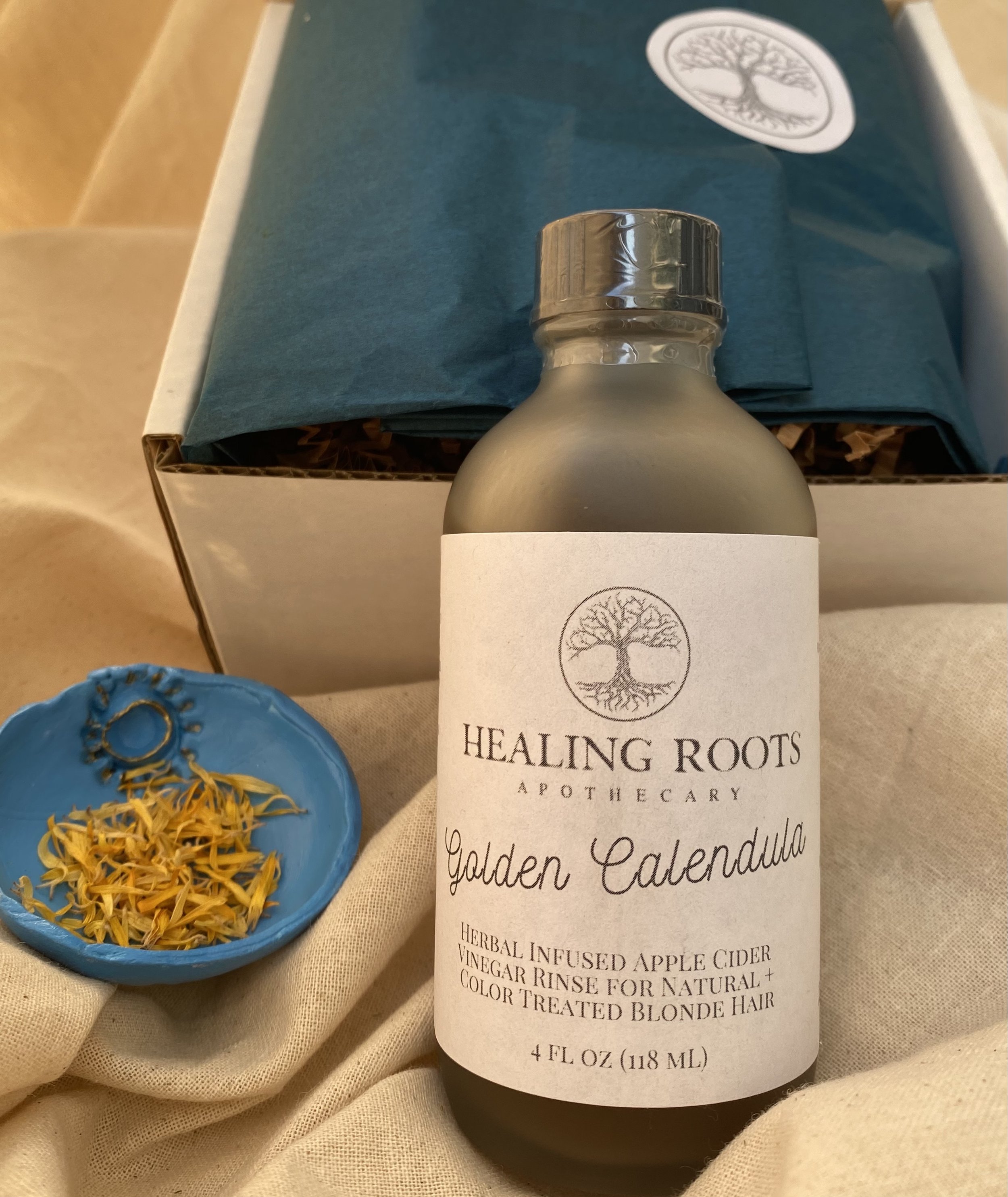Rinses are carefully packaged in a flip top box. Lining the interior of the box is peacock blue wrapping paper adorned with a circular sticker with the tree of life logo printed on it.