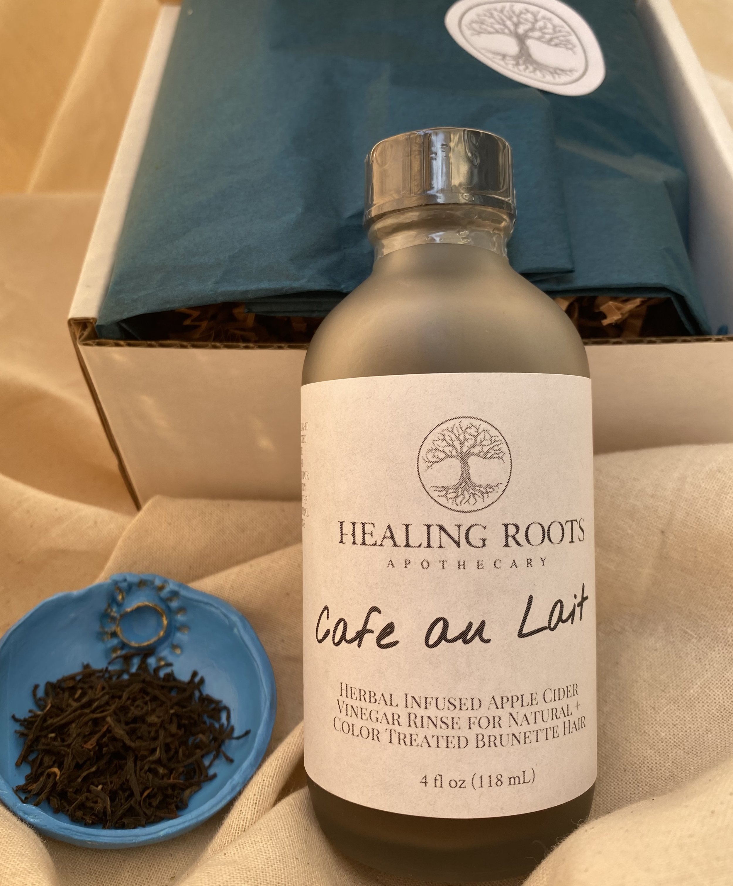 Rinses are carefully packaged in a flip top box. Lining the interior of the box is peacock blue wrapping paper adorned with a circular sticker with the tree of life logo printed on it.